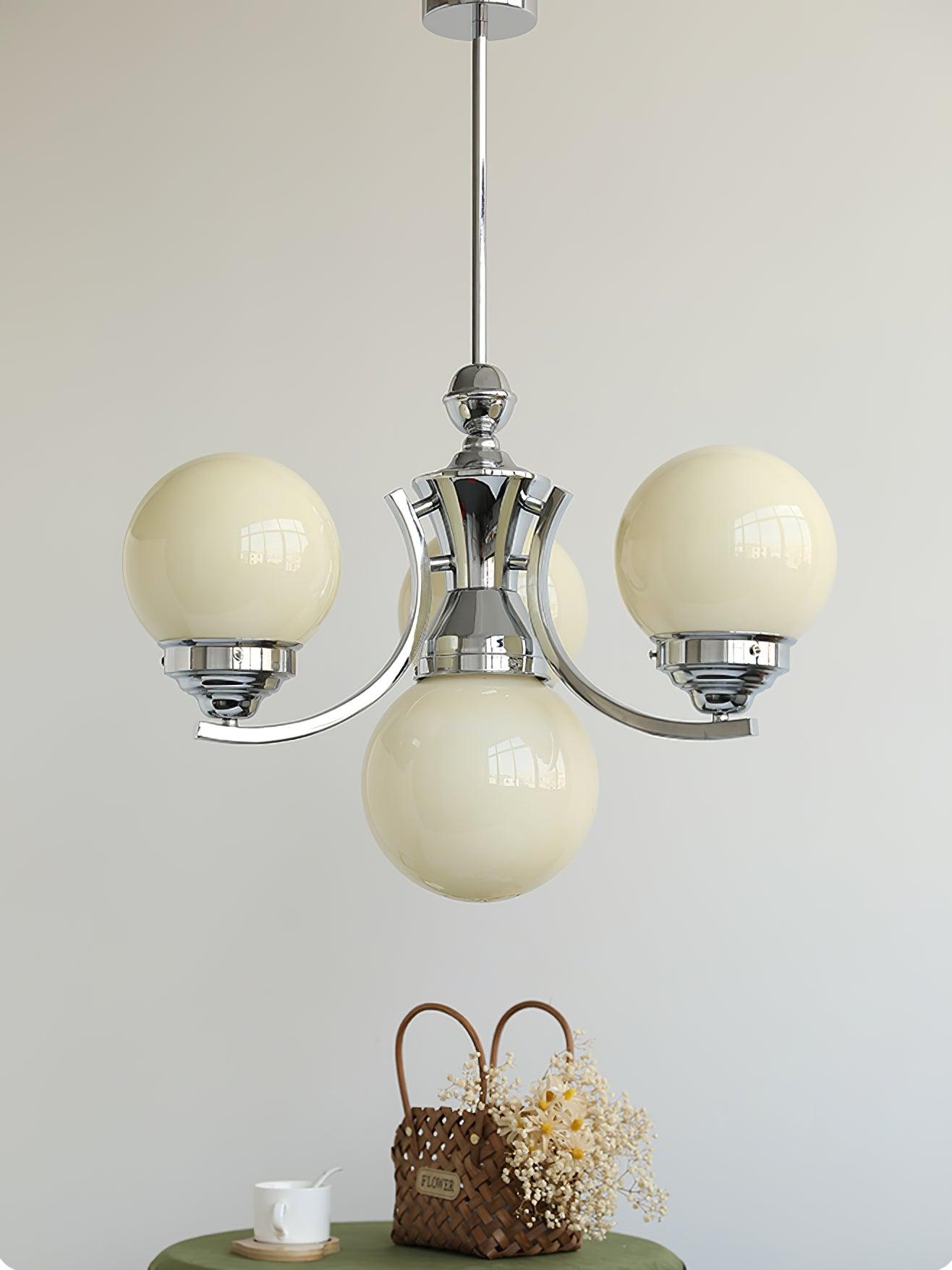 Compact cream-globe Dewdrop with rising chrome arms and a round canopy above a flower basket and green table