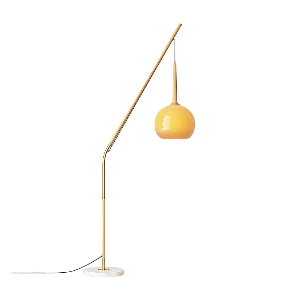 Natural wood-colour floor lamp on white with orange shade hanging right, a round marble base and black cord extending left