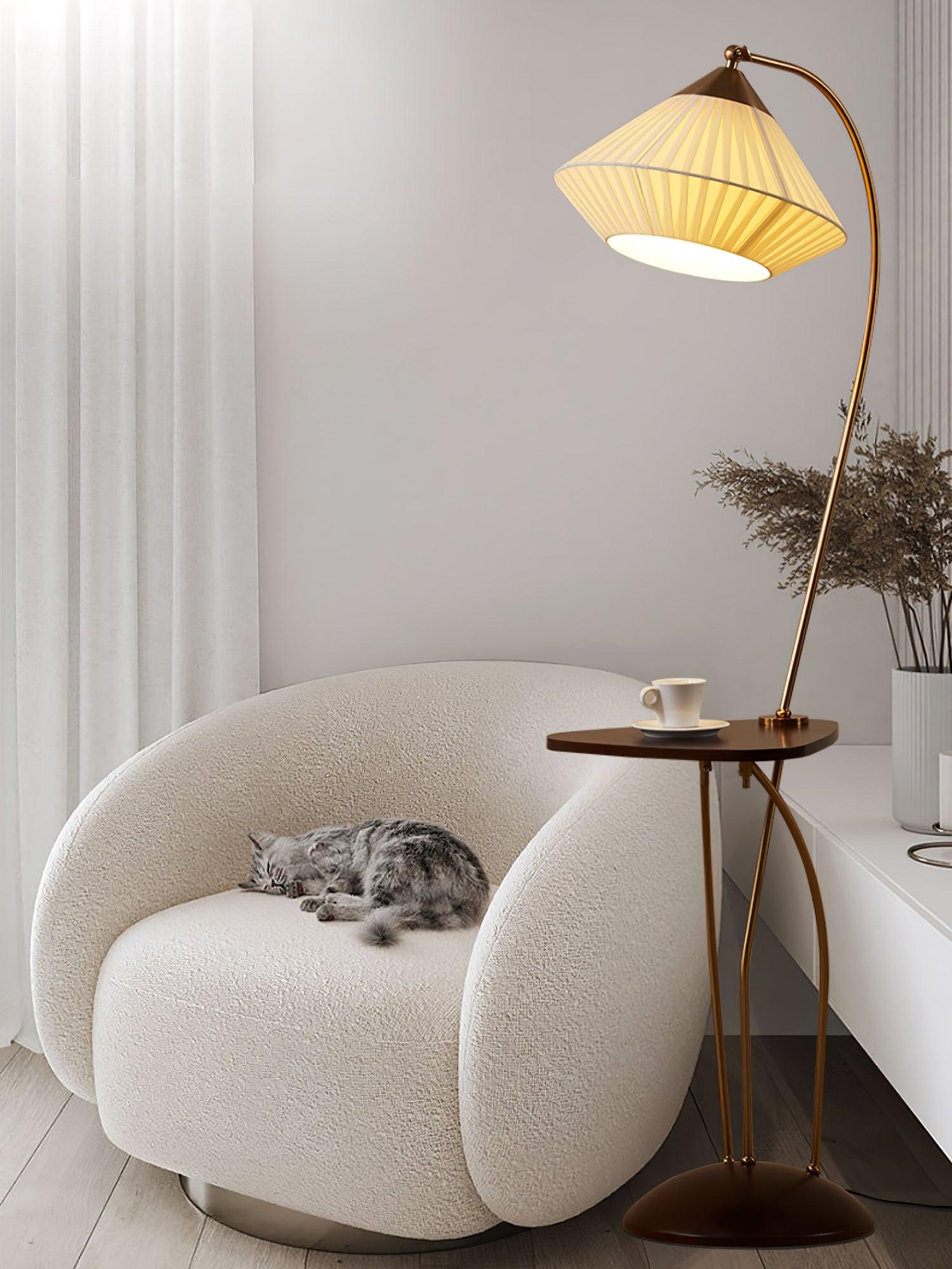 Close seating view of lit Curve and its small table beside a cream chair with a sleeping grey cat and white cabinet