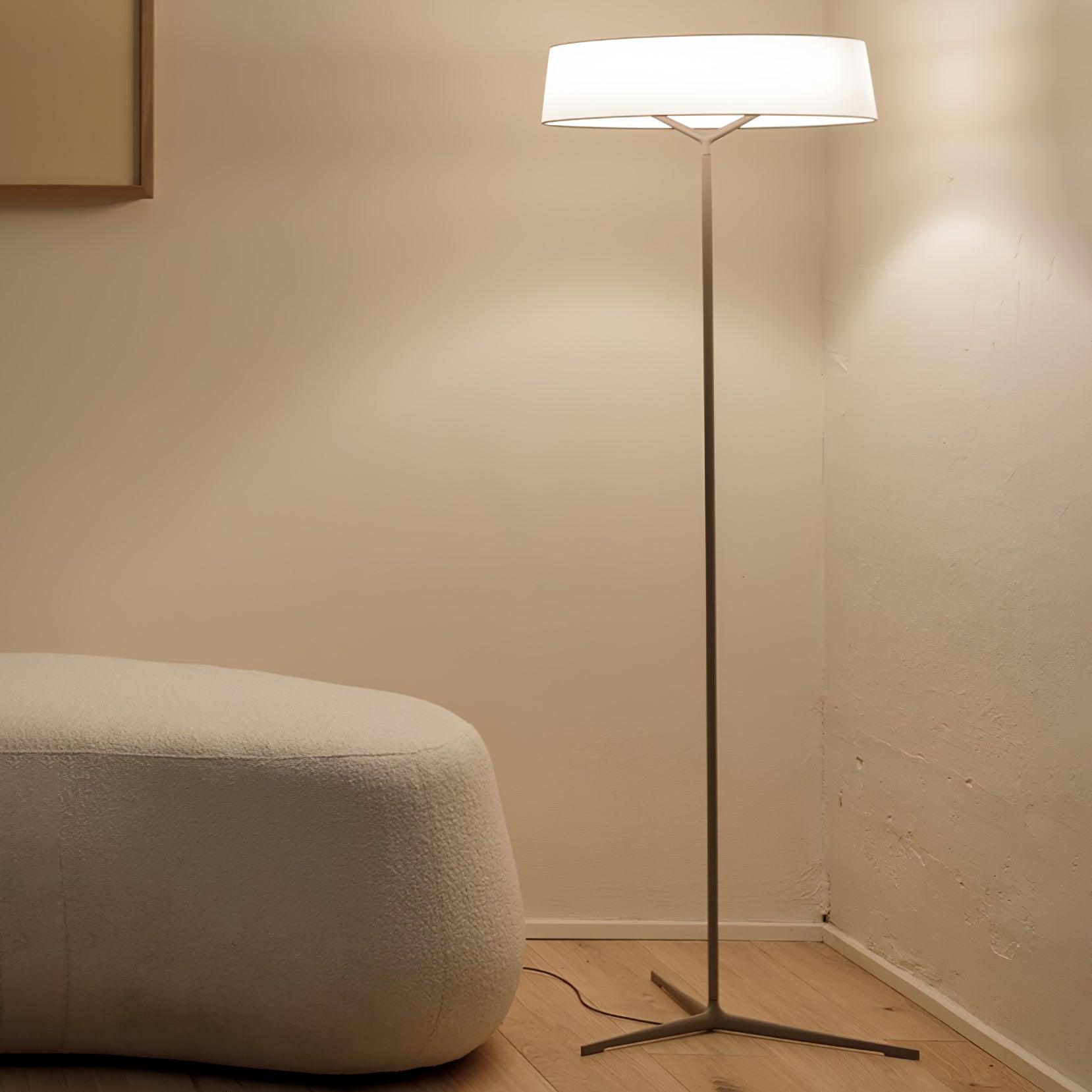 Grey floor lamp beside a rounded sofa