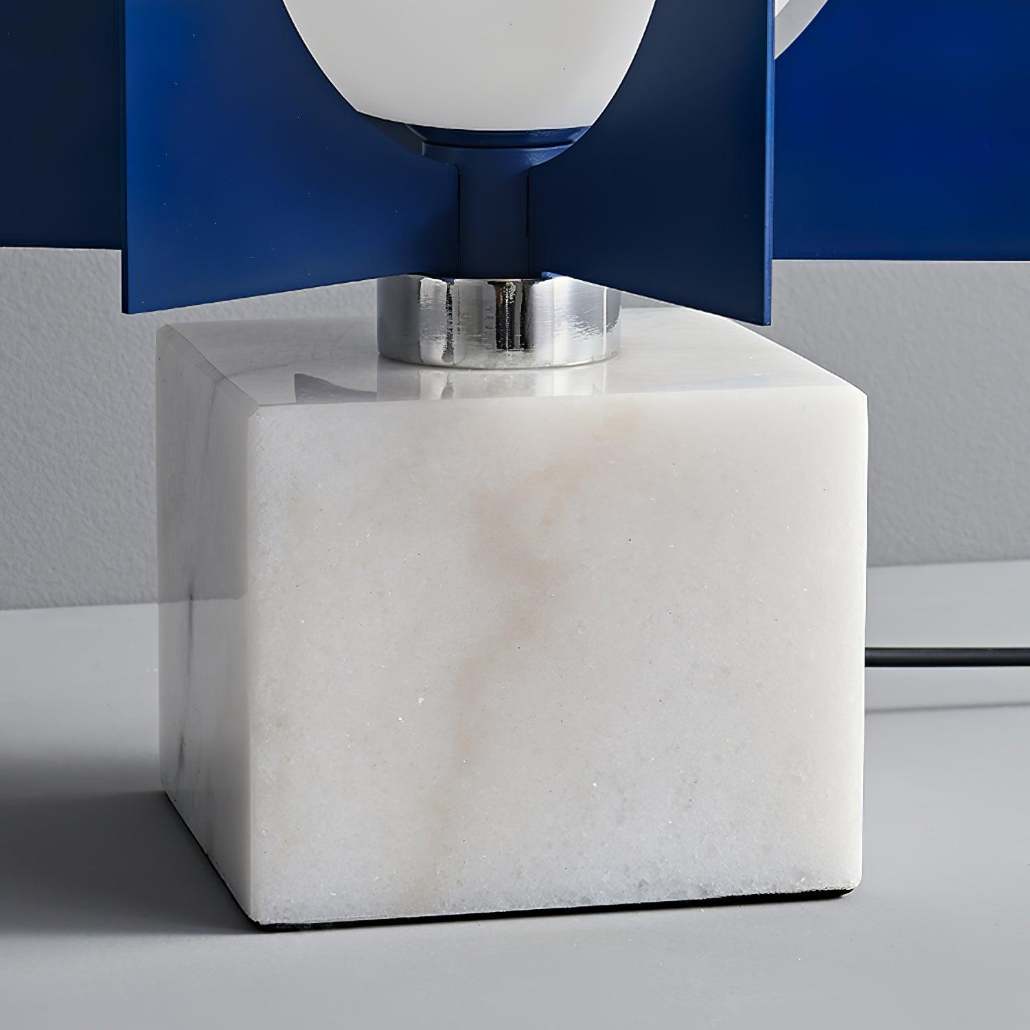 Close view of the white veined marble block and reflective collar beneath the blue column, with a black lead