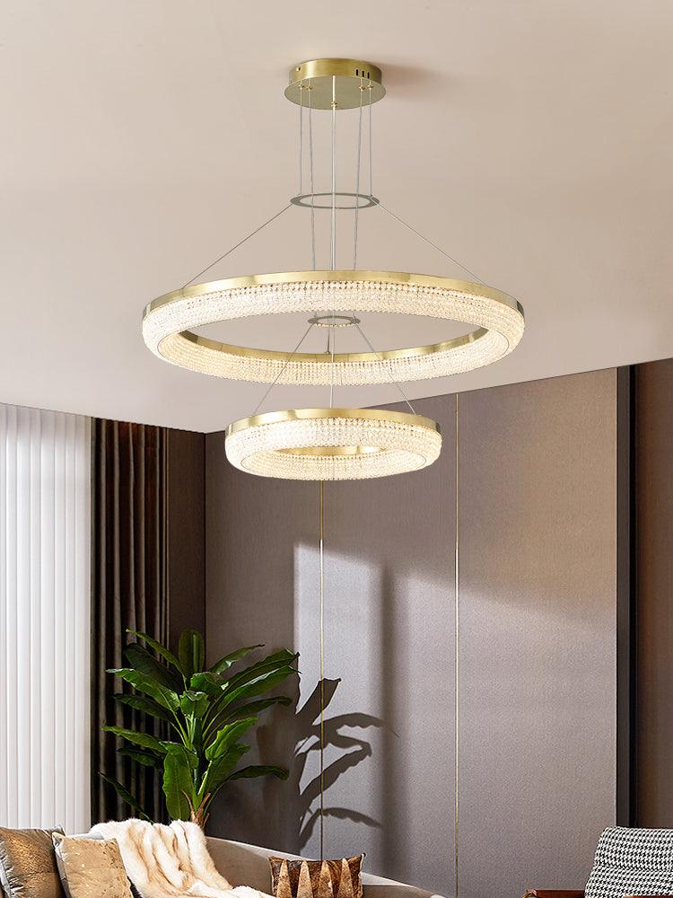 Two descending crystal rings in a living area beside a curtained window and tall plant
