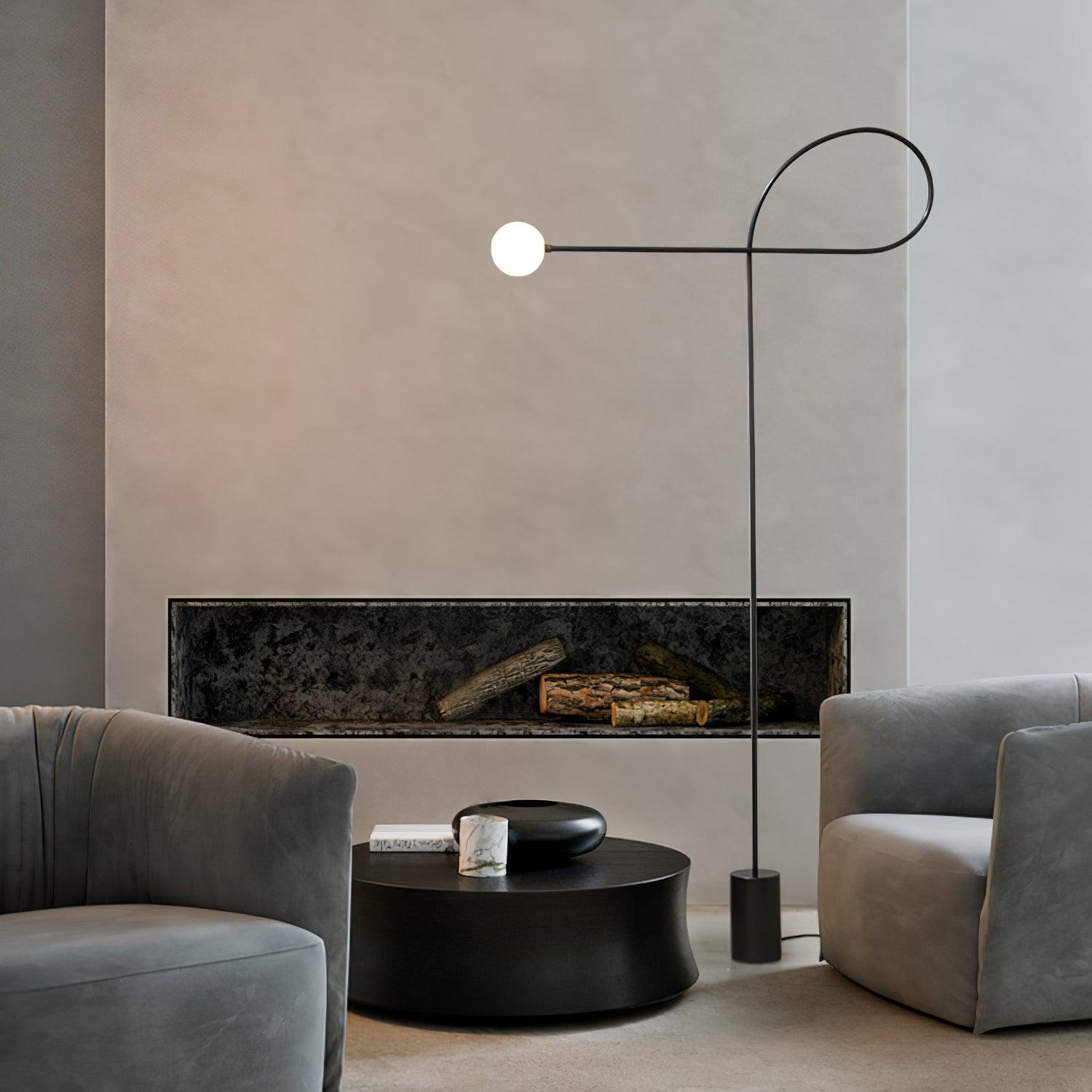 Lit black Arcane Orb lamp above a round black coffee table between grey sofas in front of a fireplace opening