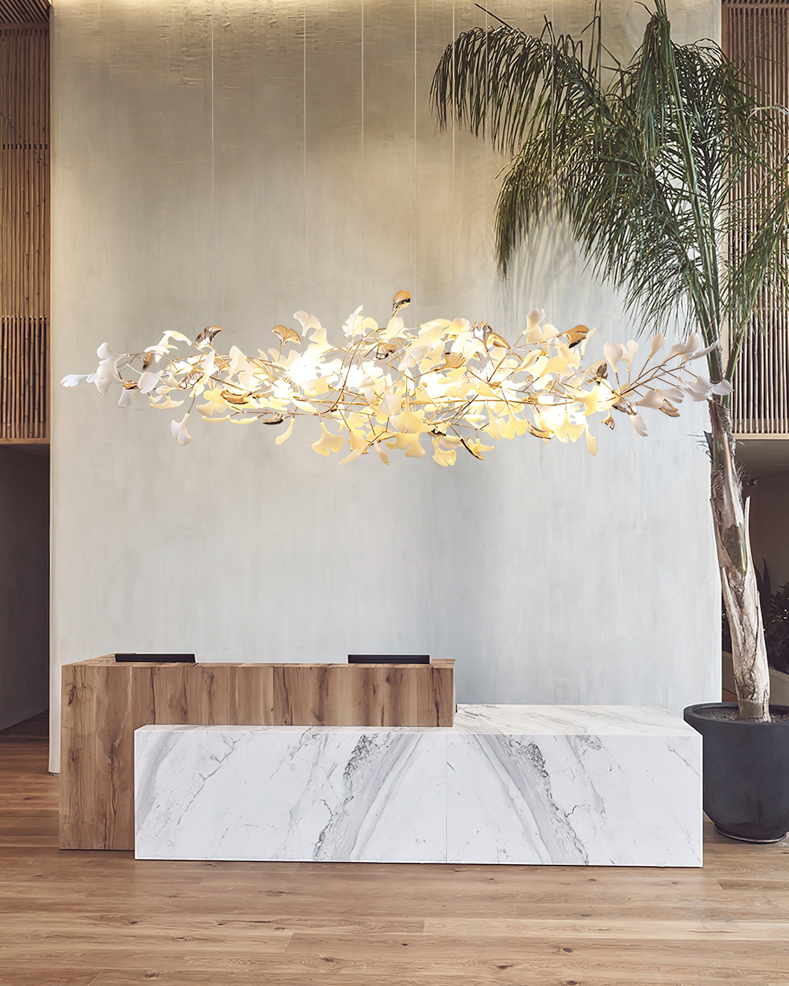 Portrait view of leaf cloud over wood-and-marble counters against pale wall, potted palm at right