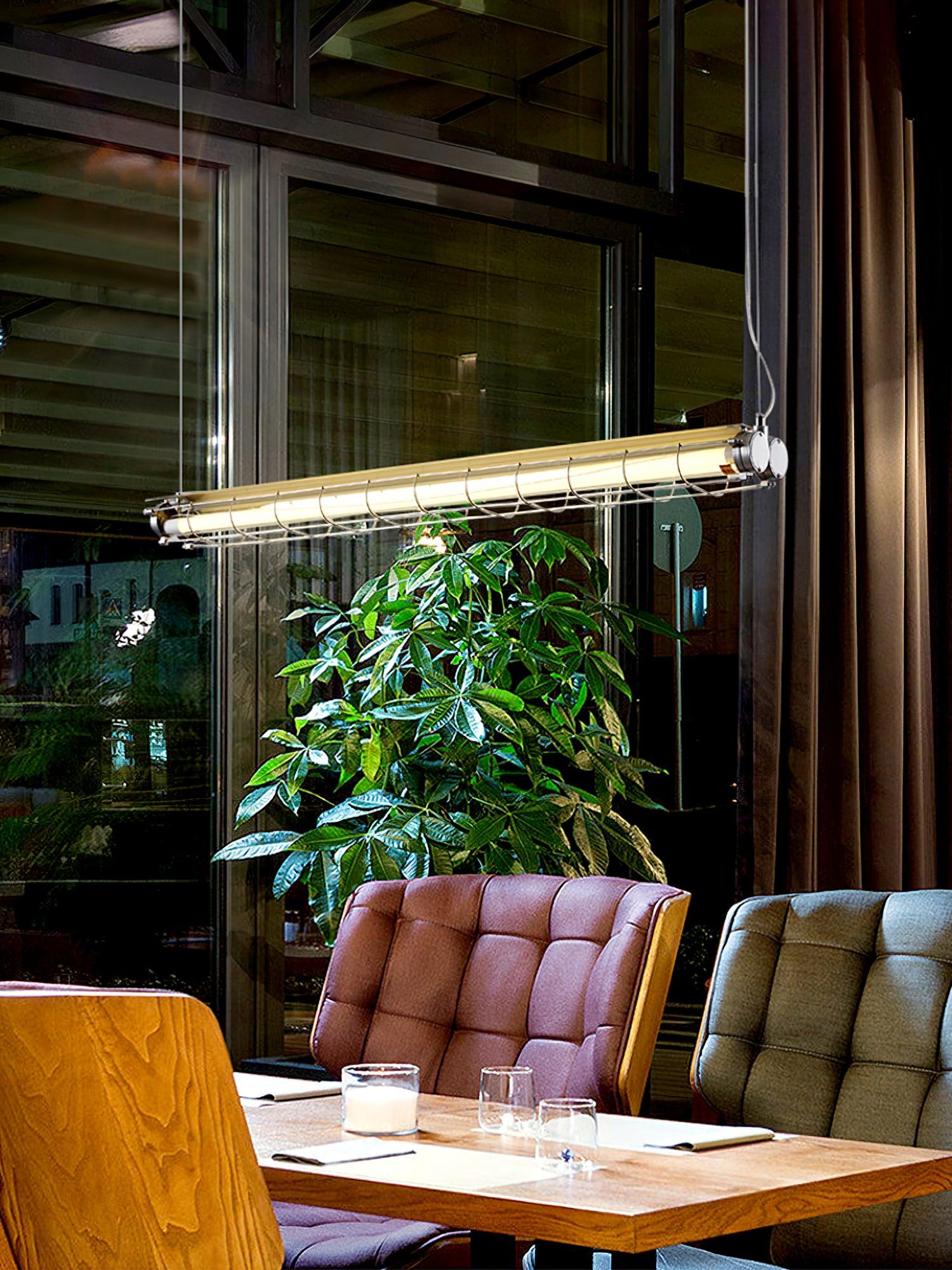 Artisan Glass light above a wooden table, upholstered booth seating and a leafy plant