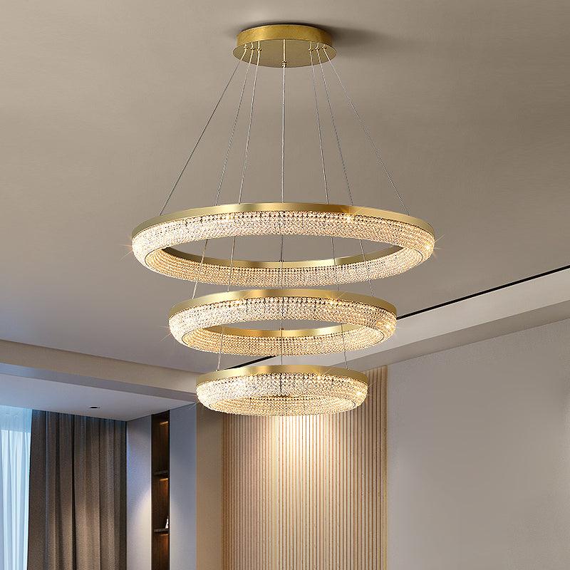 Three descending illuminated crystal rings with gold rims beside timber wall panels and curtains