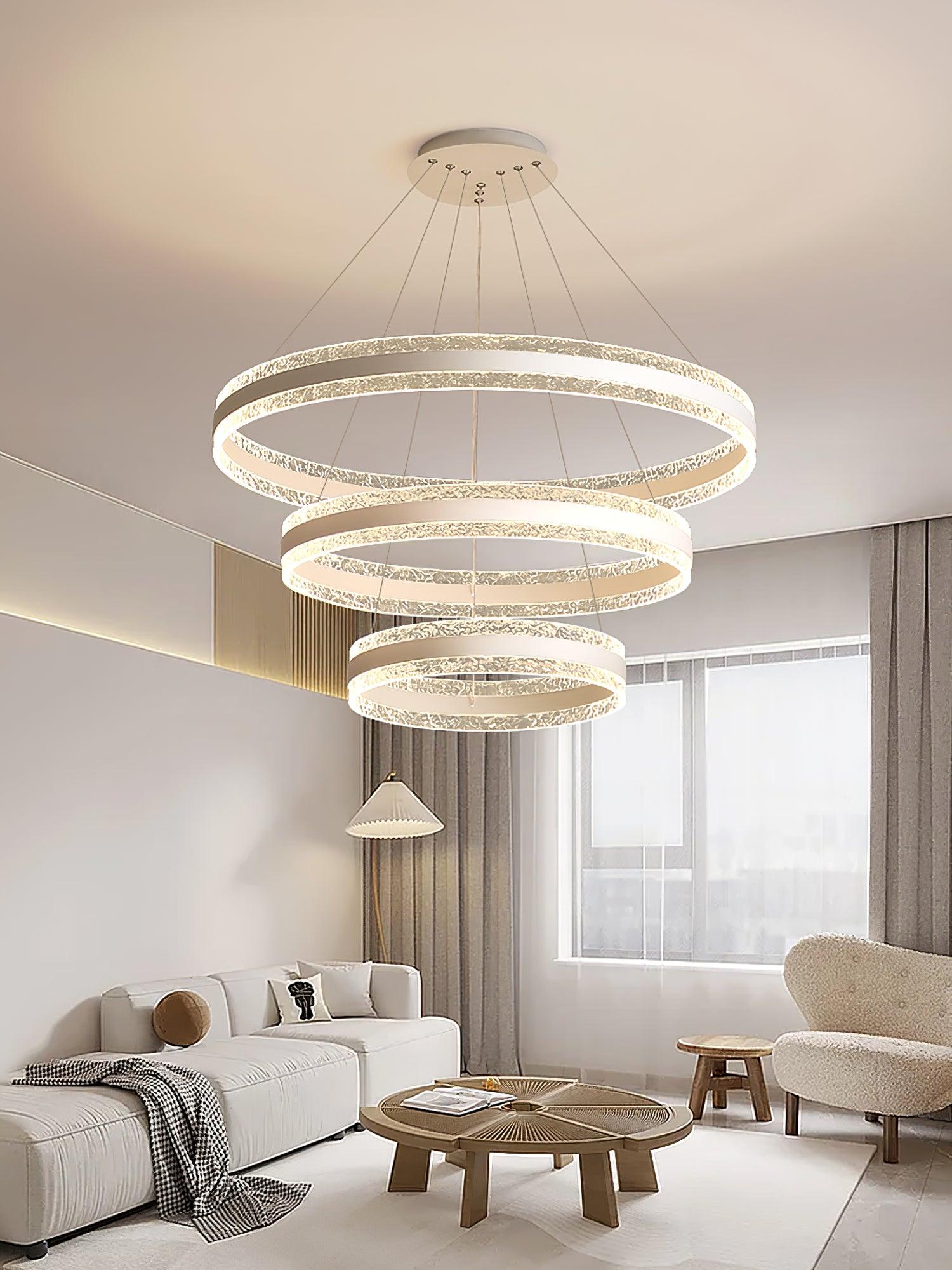 Three horizontal LED rings in descending sizes above grey living-room seating and a round coffee table