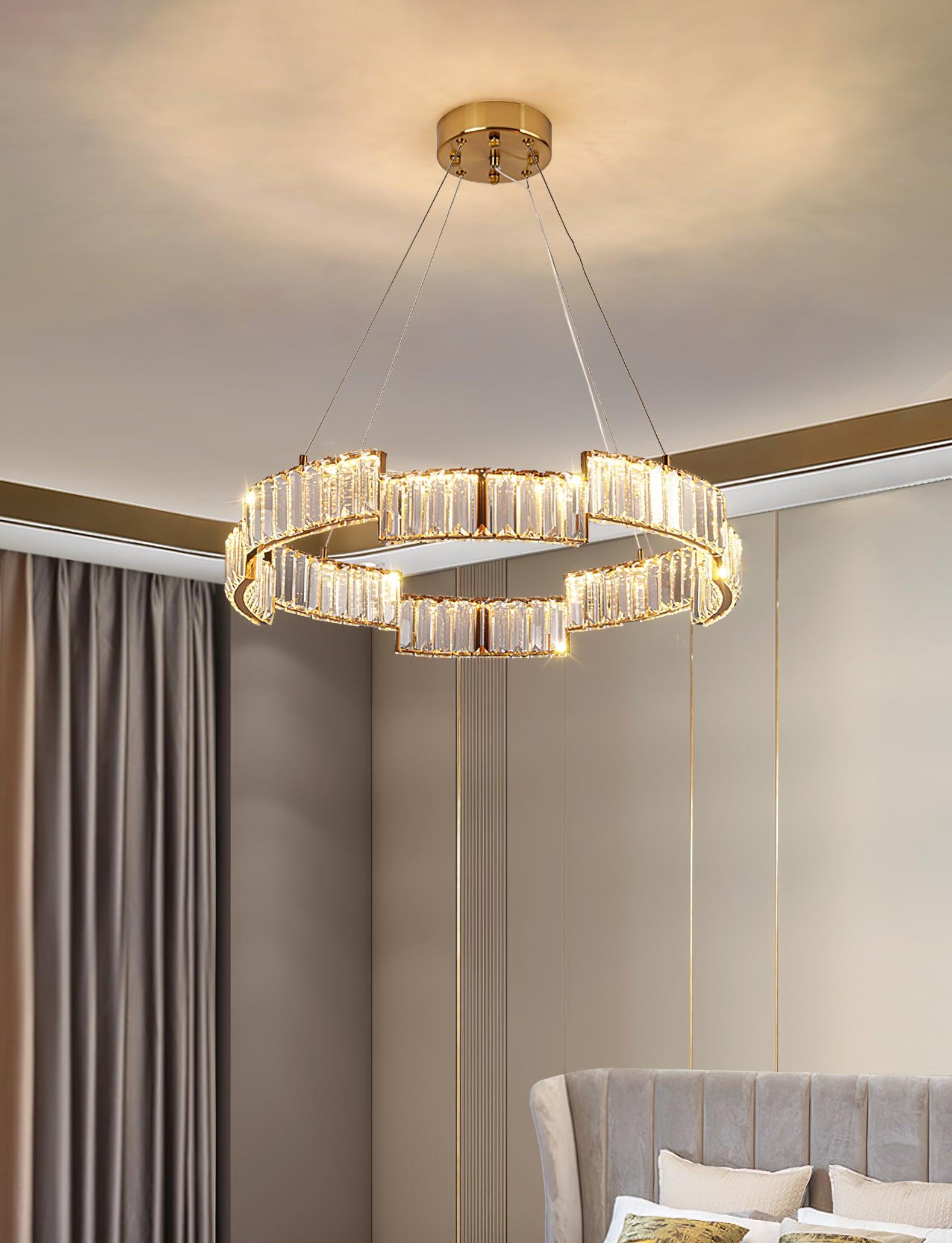 Close lit stepped ring chandelier above a grey upholstered headboard beside curtains and vertical gold wall trim