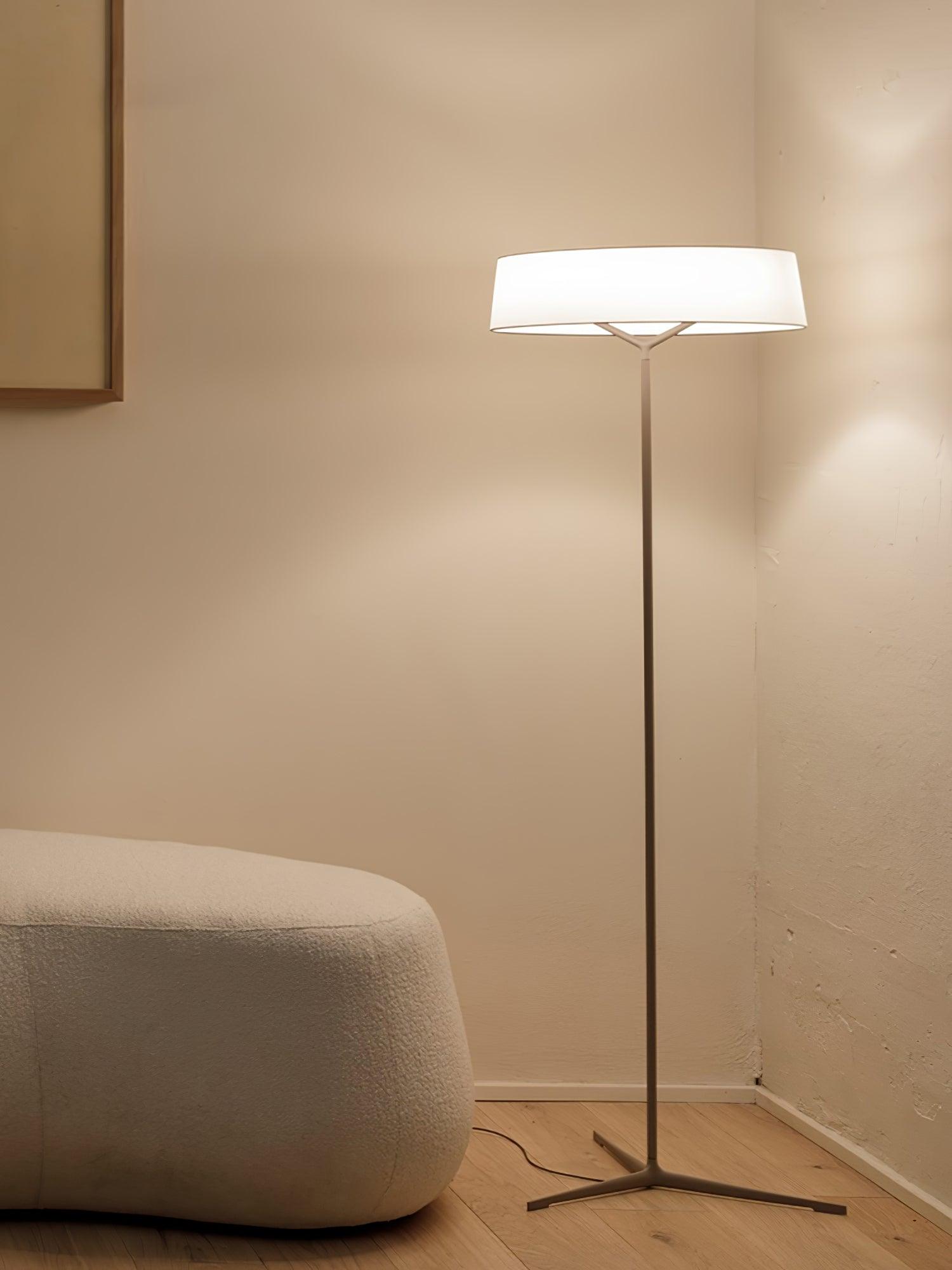Circular floor lamp in a pale living-room corner