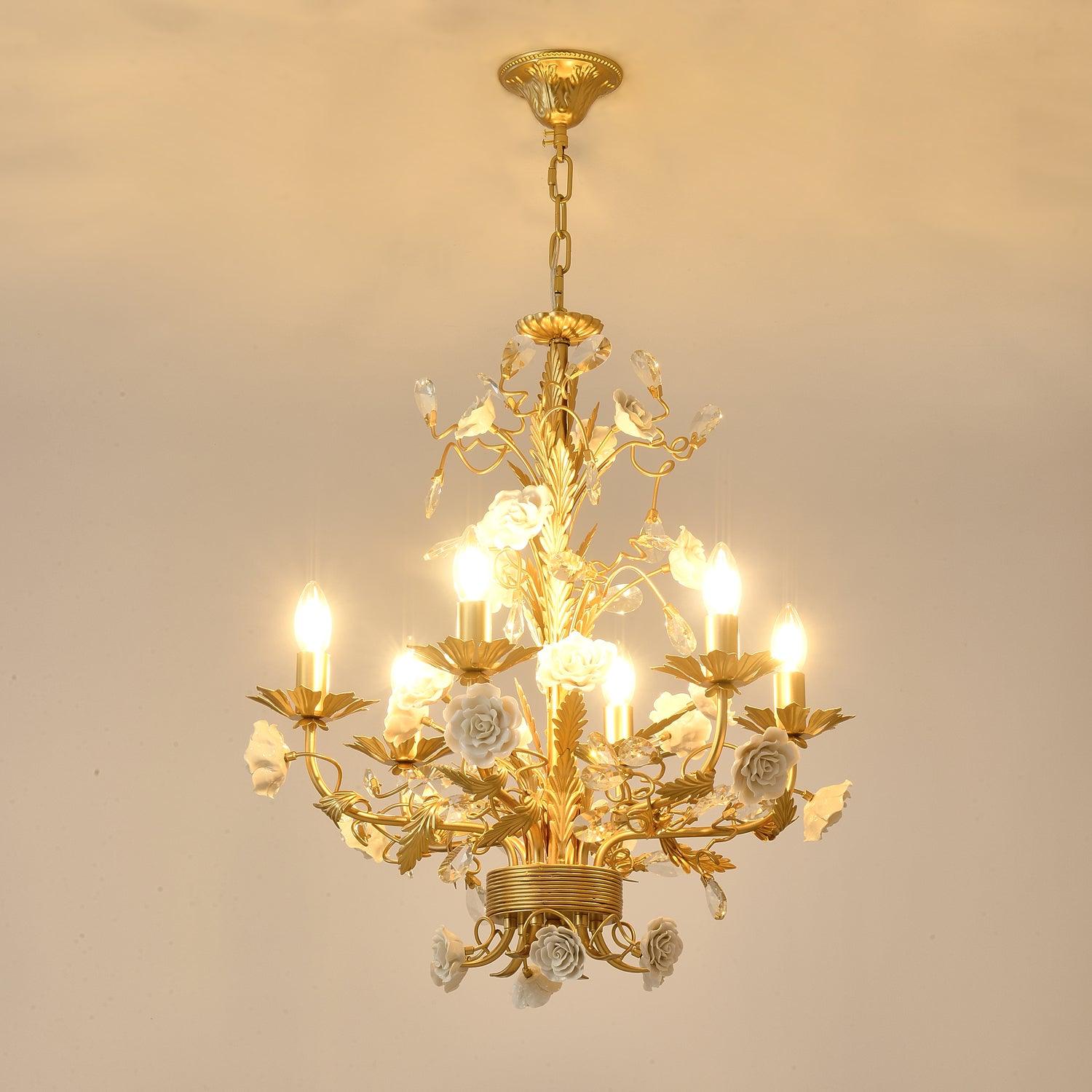 Warm-lit floral chandelier against beige wall, with embossed canopy, exposed chain, white roses and clear crystal ornaments