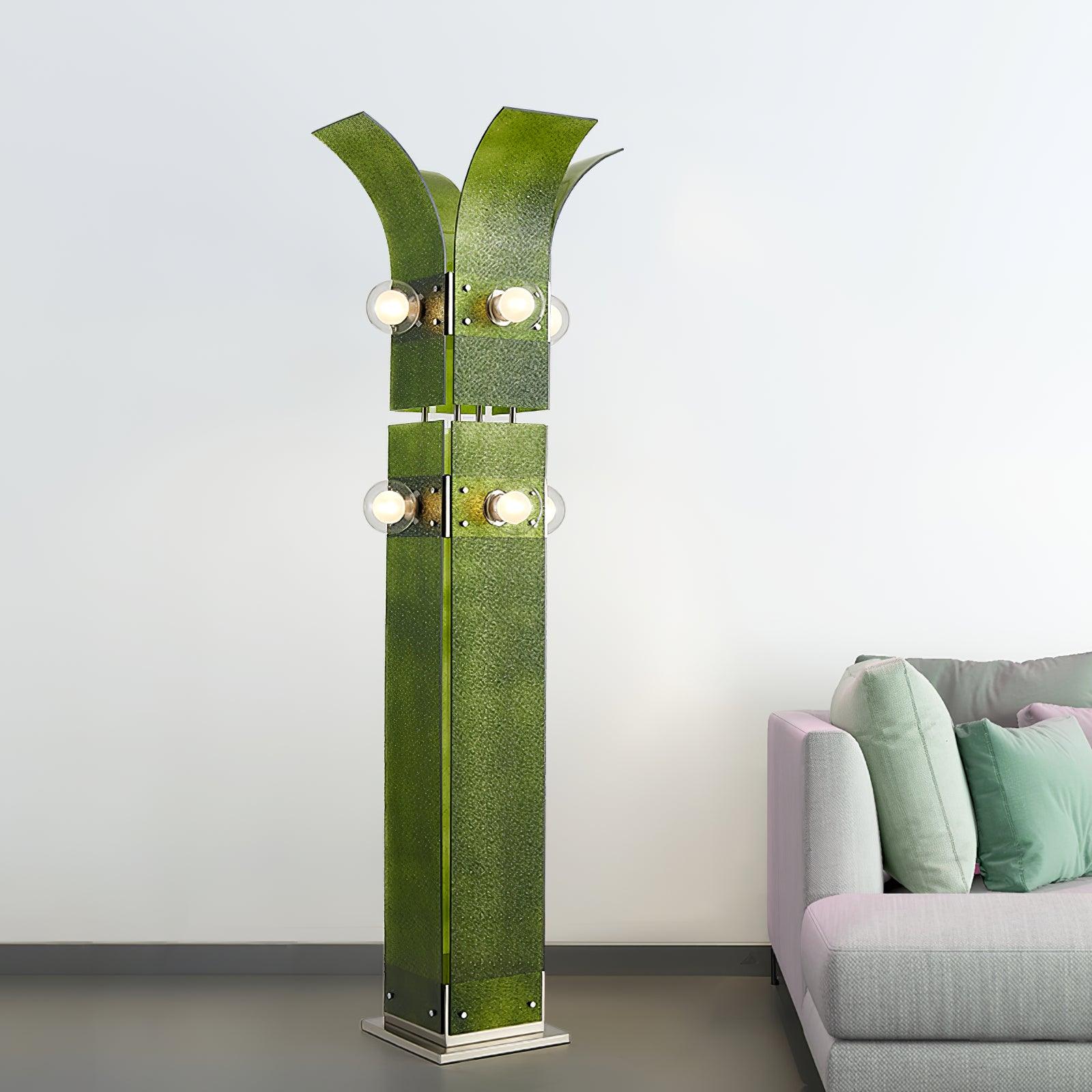 Full Green floor lamp beside pale sofa and mint cushions, with outward-curving crown, two levels of round lights and stepped base