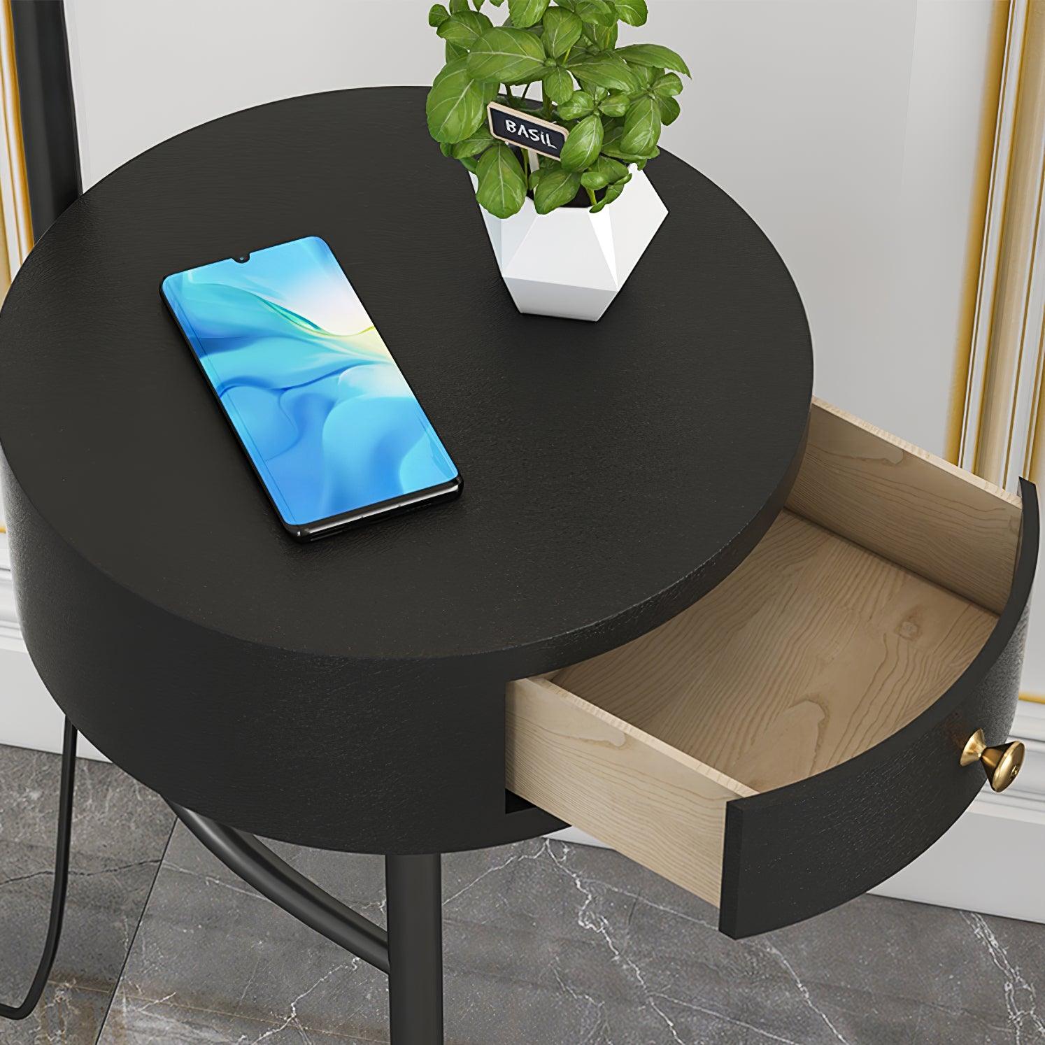 Close black round table with phone and potted plant, open pale wood drawer, curved black front, gold knob and black frame