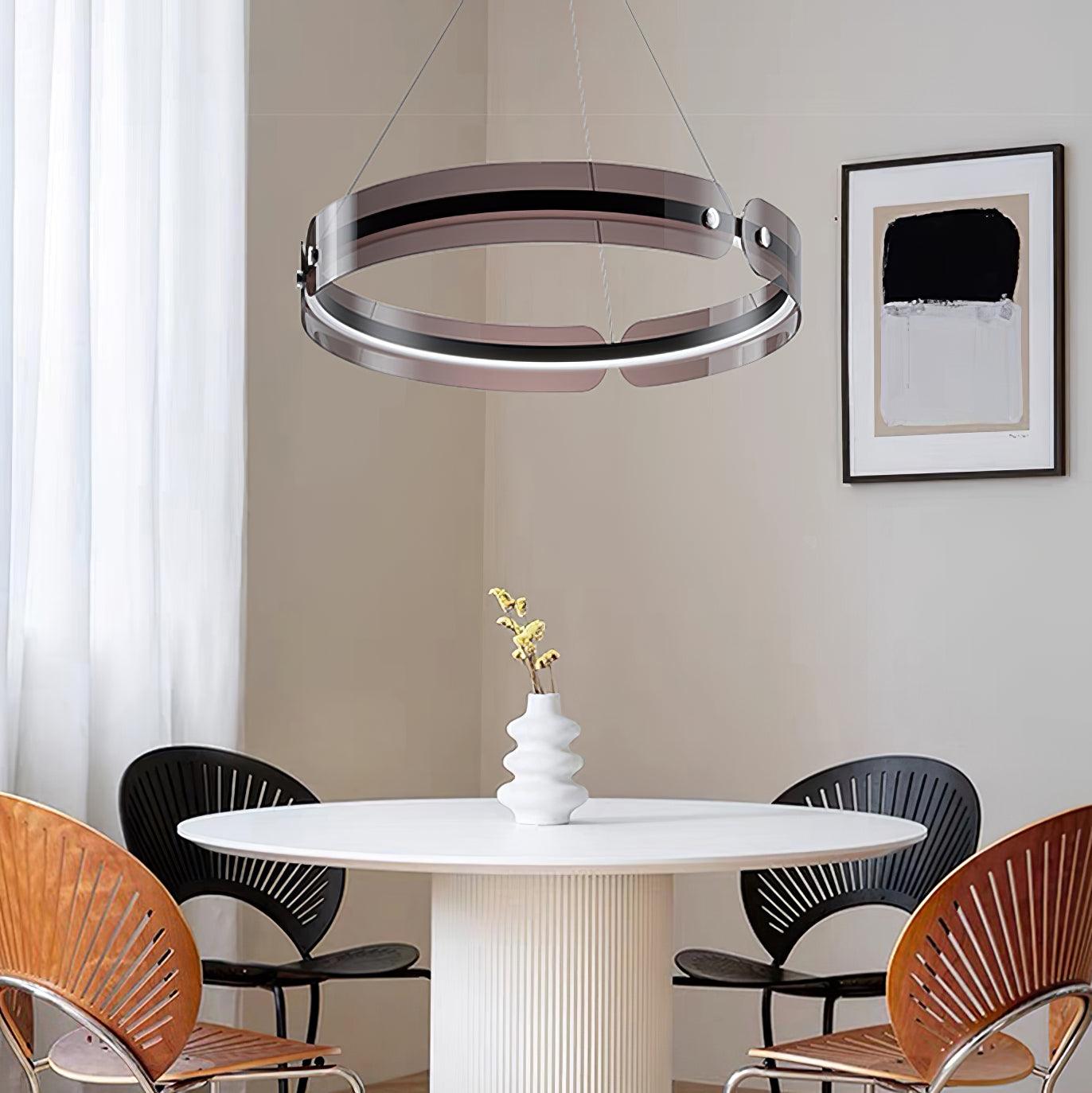 Javor coffee-tinted ring above a round white dining table with black and wood chairs beside sheer curtains