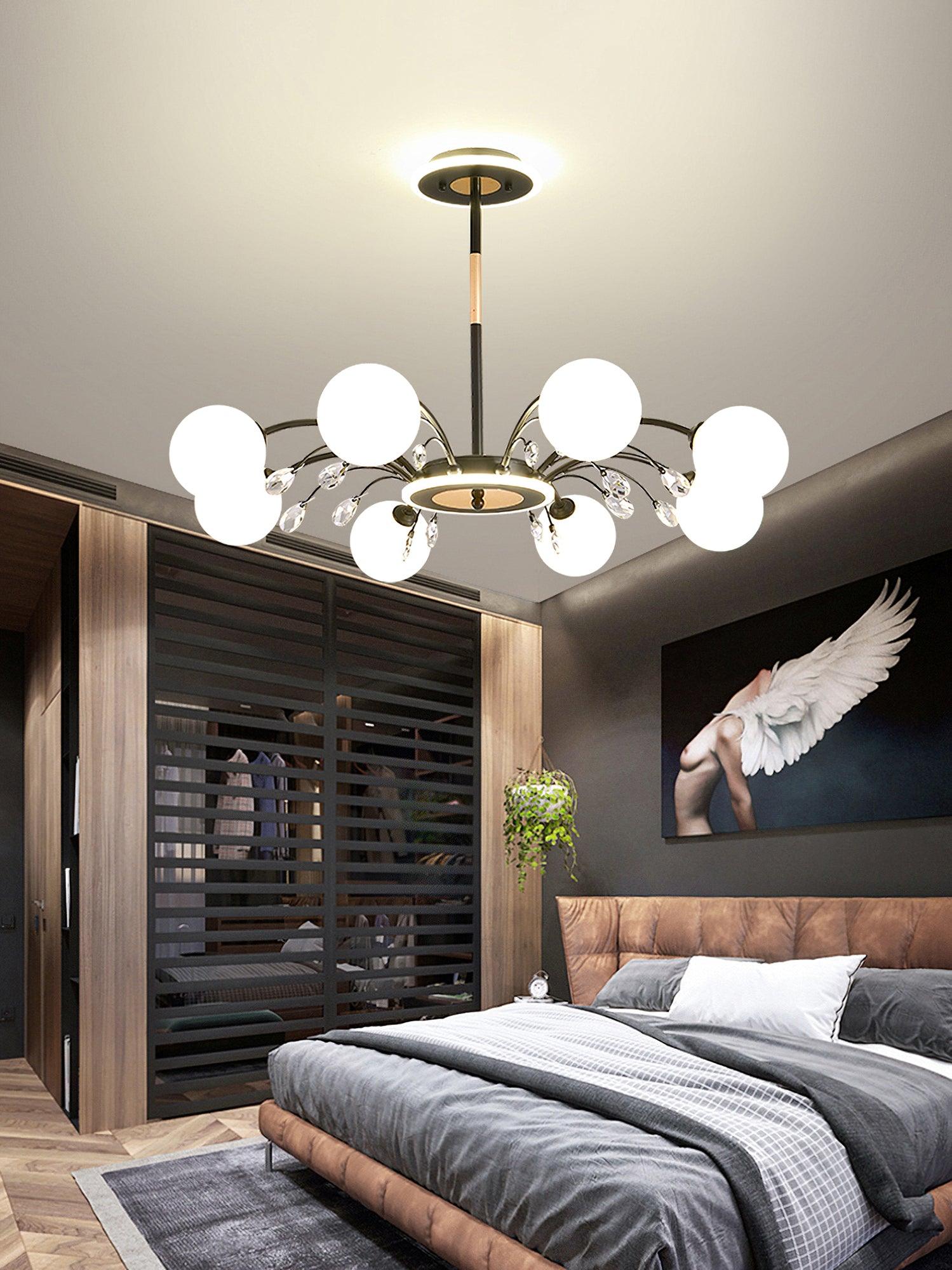 Black globe chandelier above bed with wood-slatted partition, hanging plant and winged-figure artwork