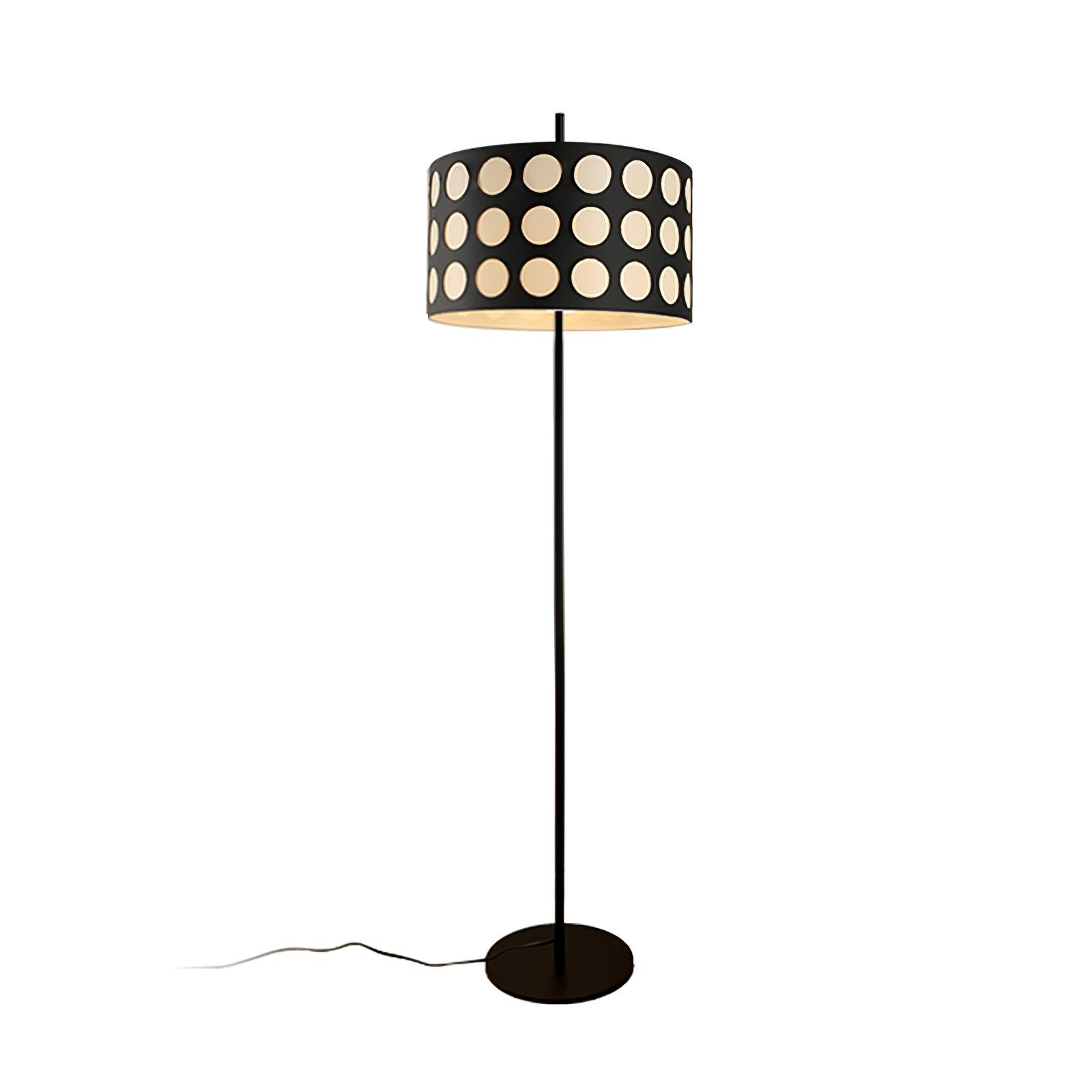 Isolated straight black floor lamp with pale dotted drum shade, circular base and cord against white background