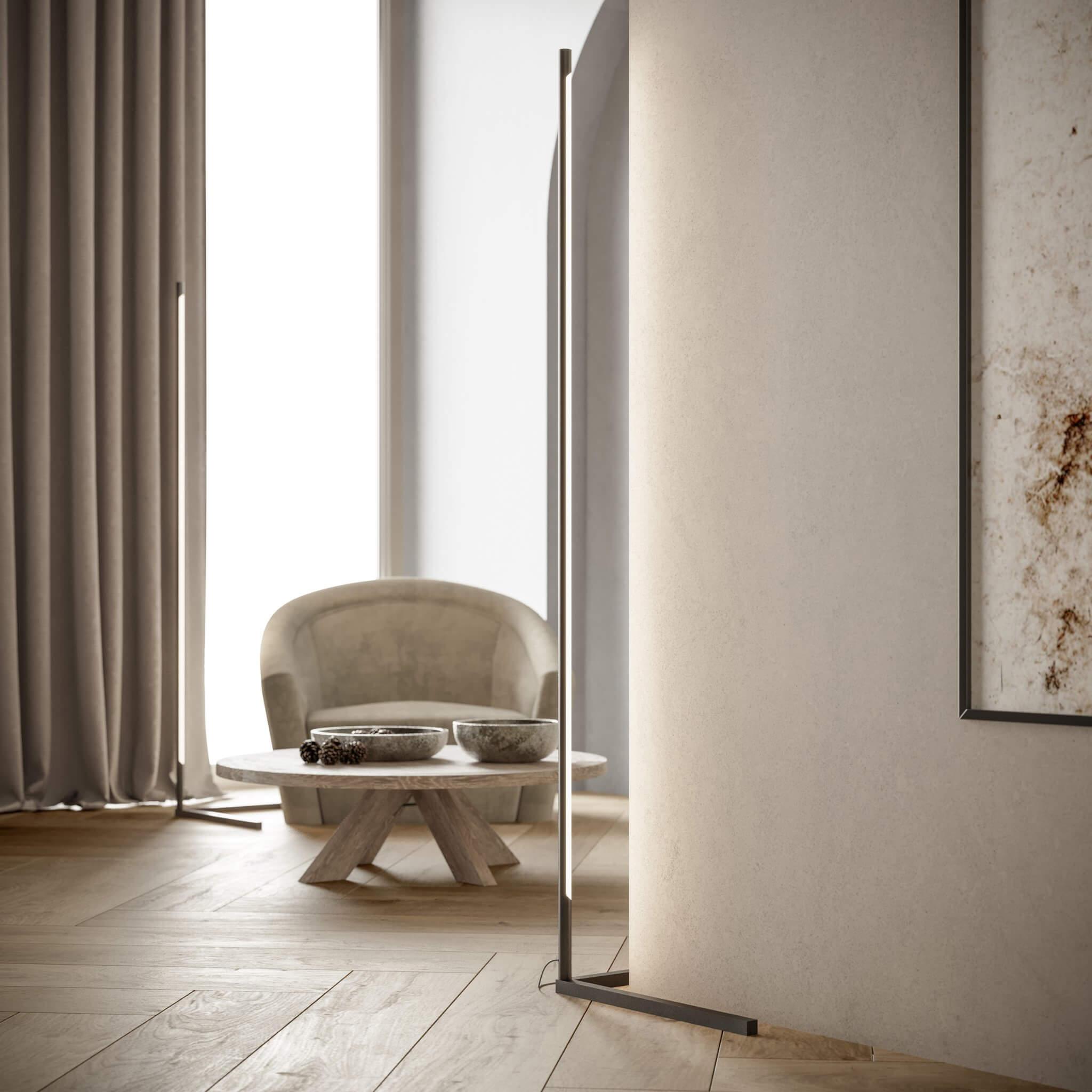 Slim floor lamp beside a projecting wall, with another similar lamp visible near curtains in the background