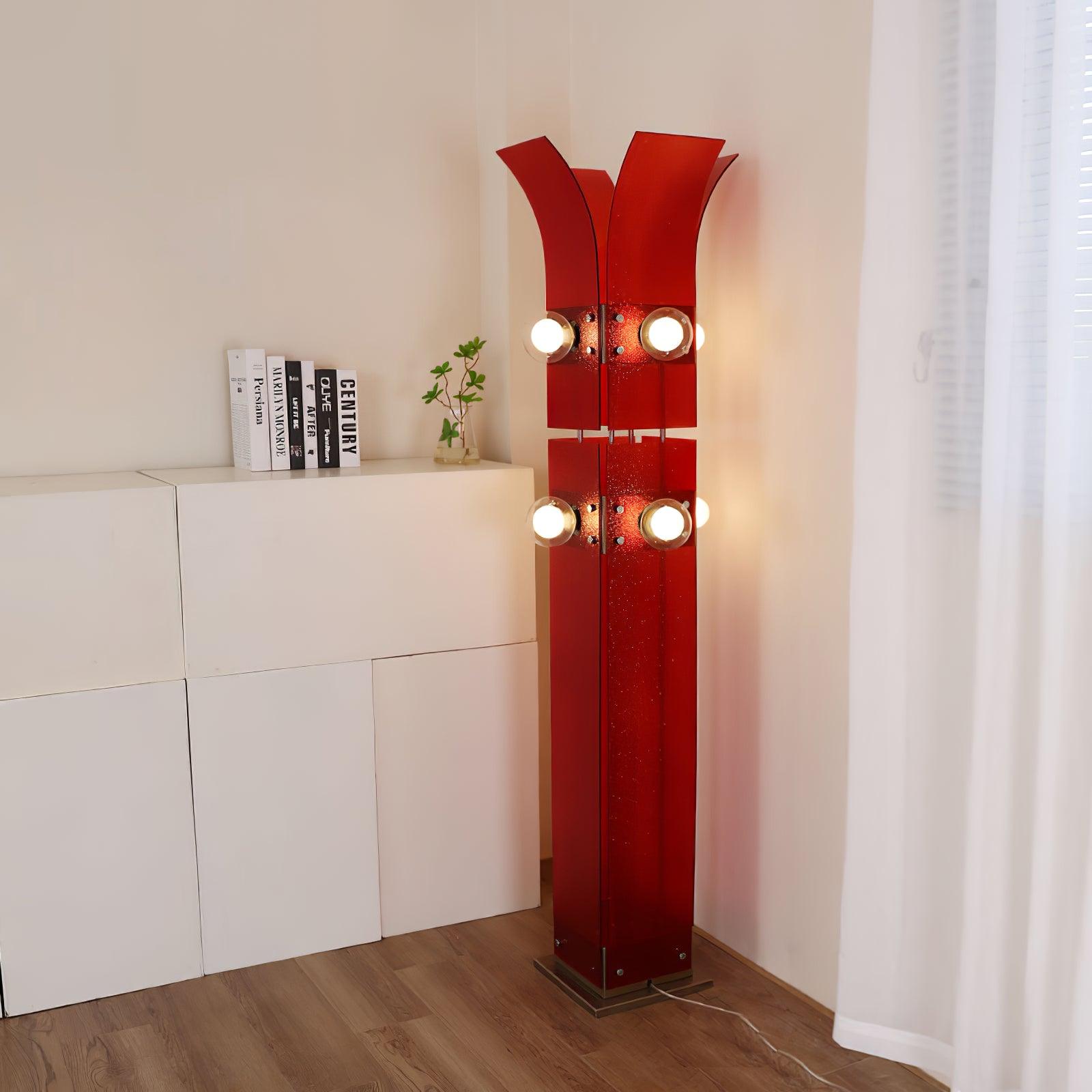 Red palm-shaped floor lamp beside white block cabinet, books, small vase and white curtain, with two levels of round lights and cord