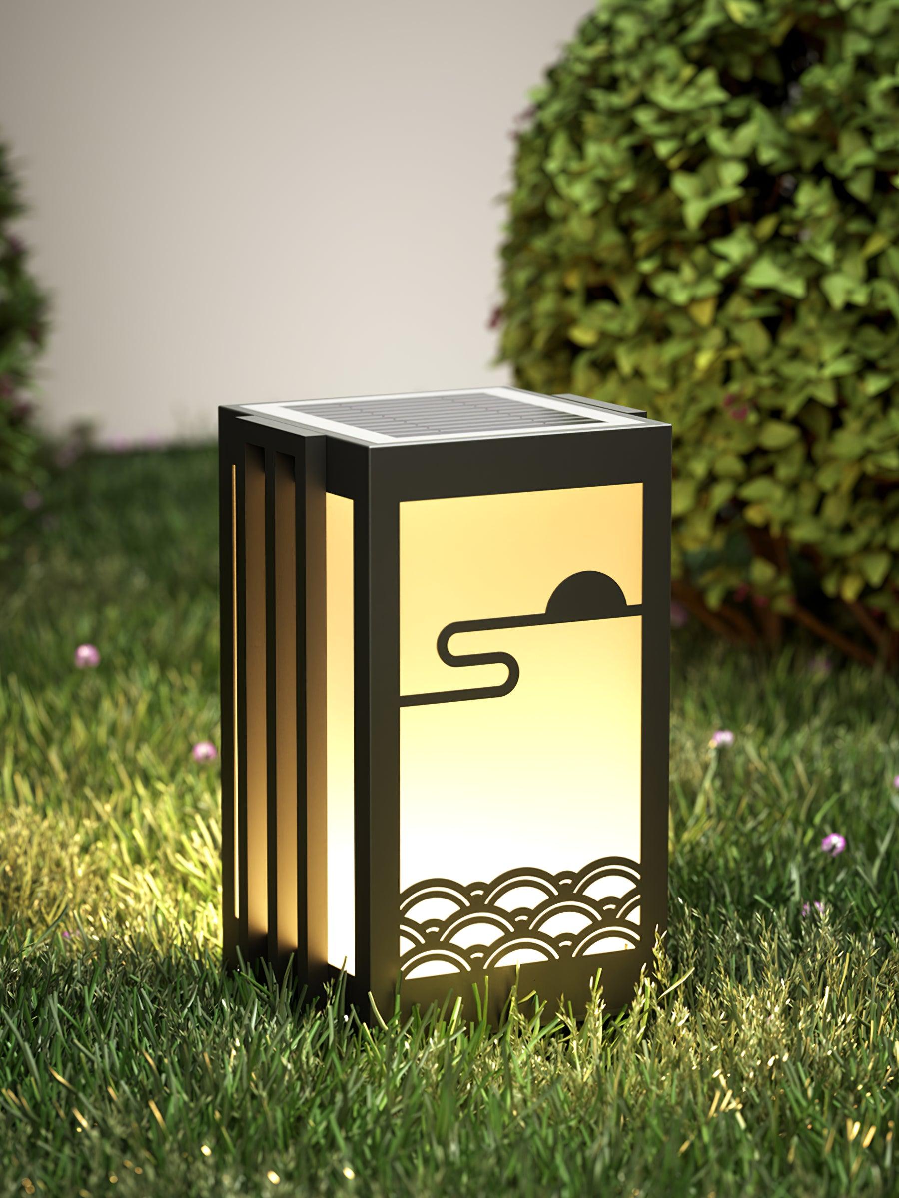 Short solar garden lantern on lawn, showing top solar panel, black frame, pale sun-and-wave front and side fins