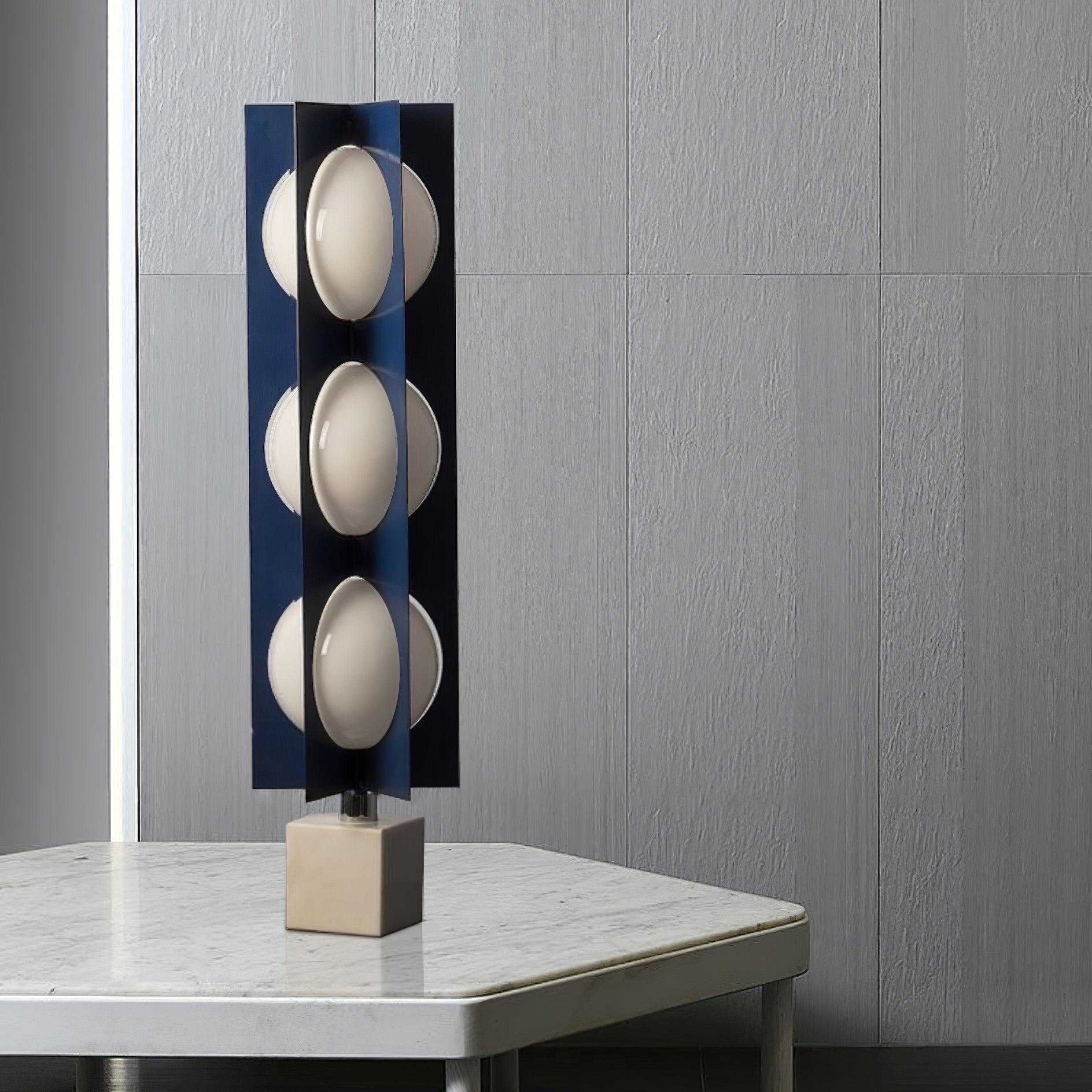 Three white convex shade levels between blue fins on a marble table against a textured wall