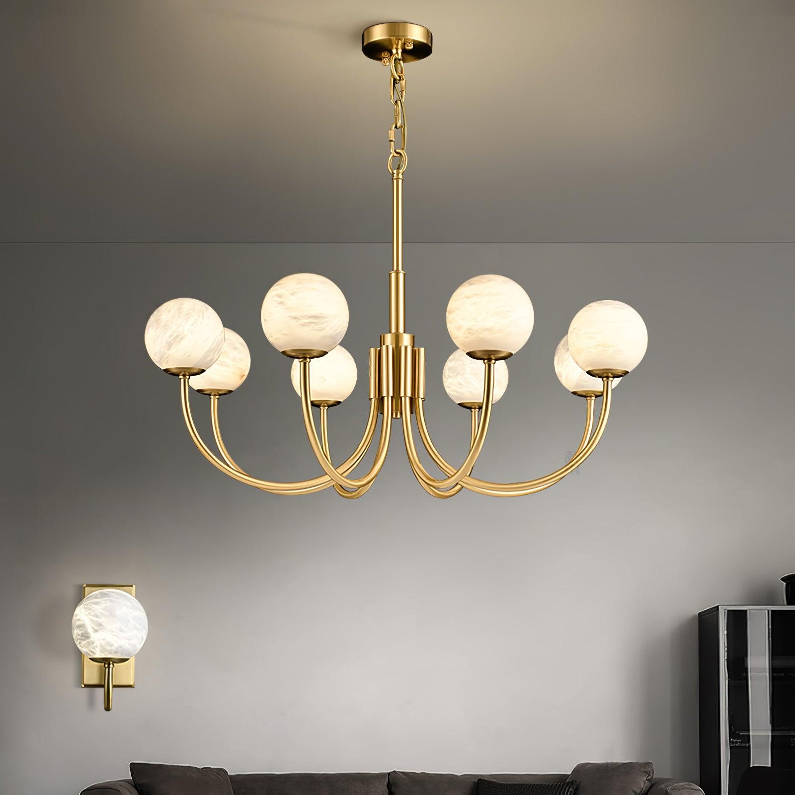 Brass chandelier above a sofa beside a separate wall light