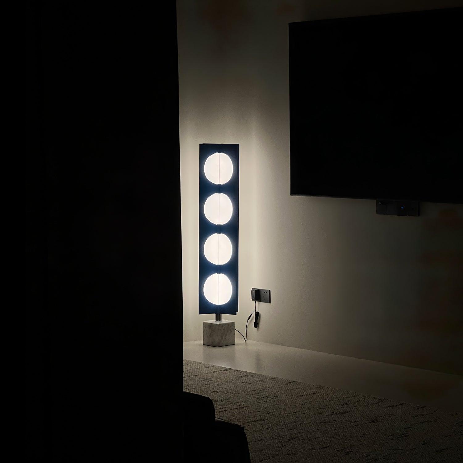 Four glowing circular shade levels on a blue column below a television, with lead, plug and inline switch visible