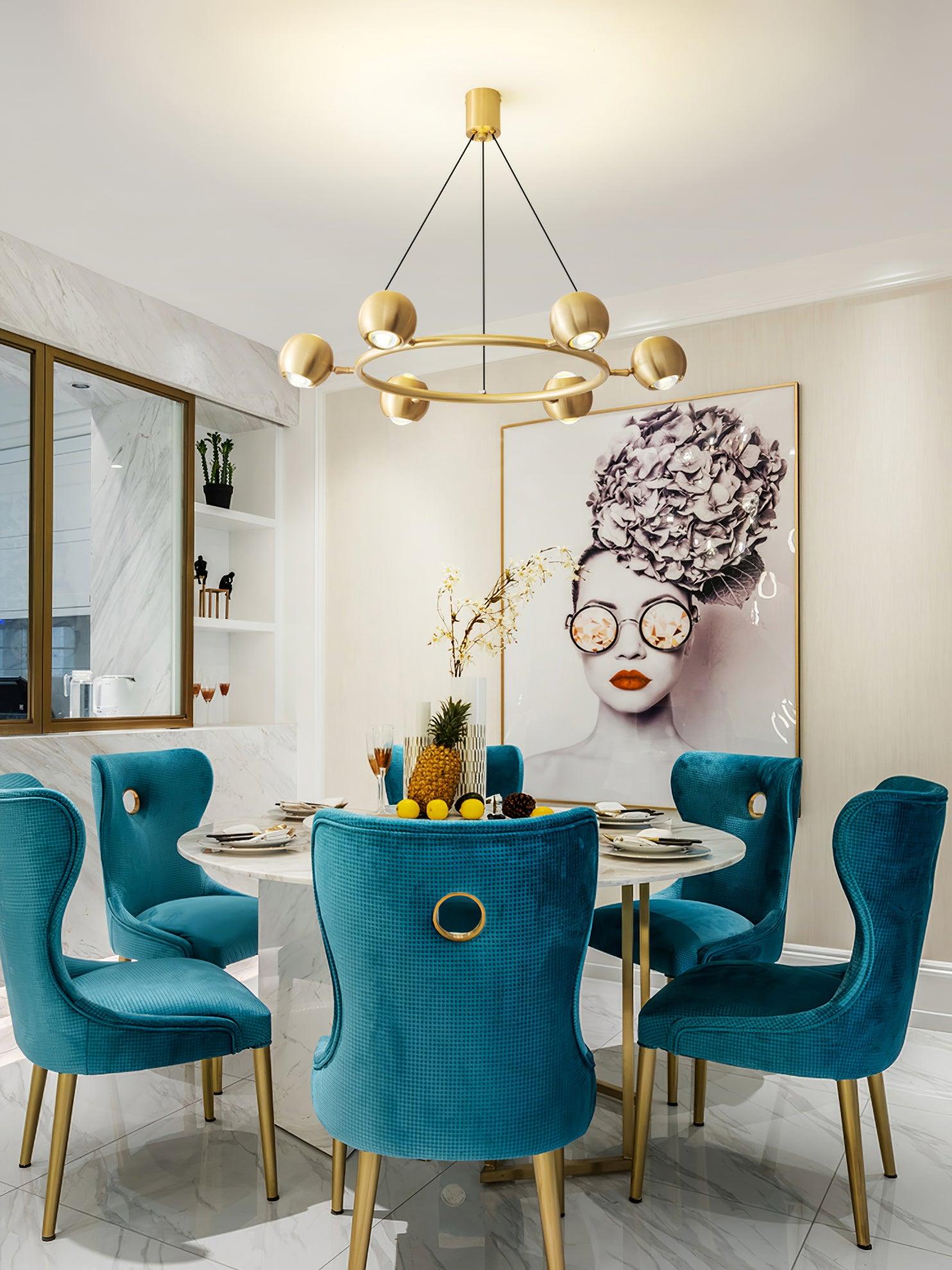Brass chandelier above a dining table and turquoise chairs