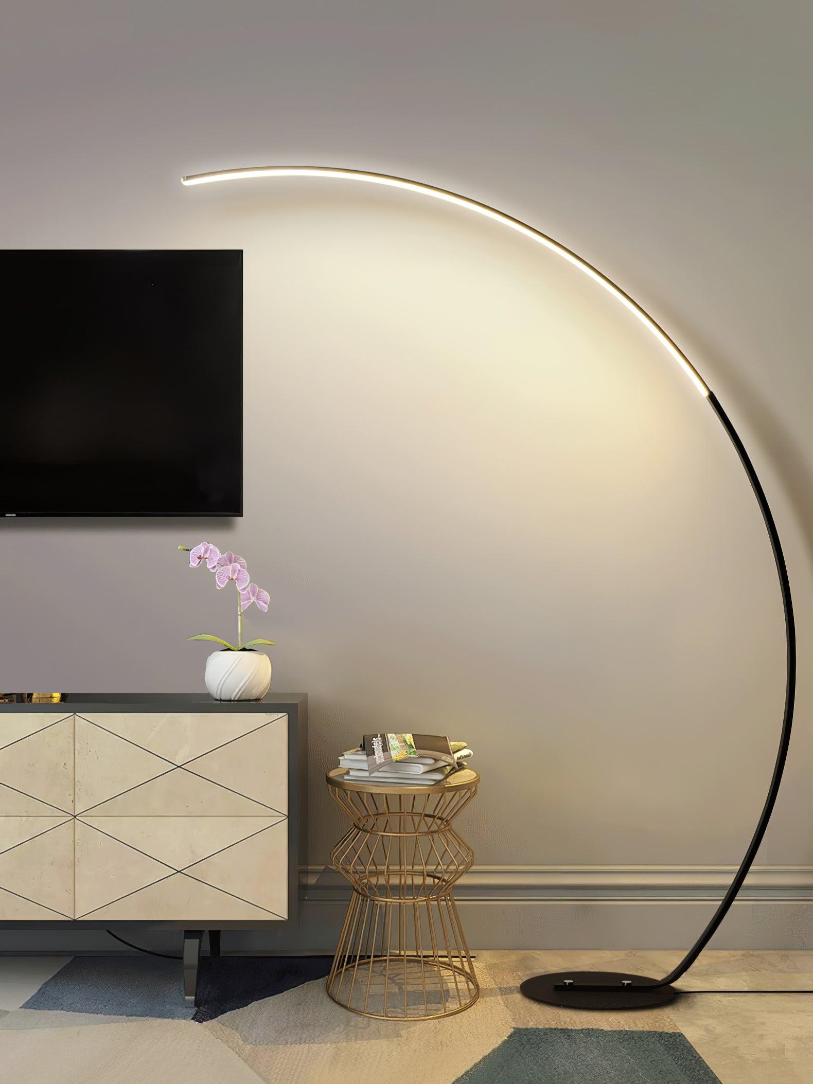 Black lit Arc floor lamp beside television cabinet, orchid and wire-frame side table with books