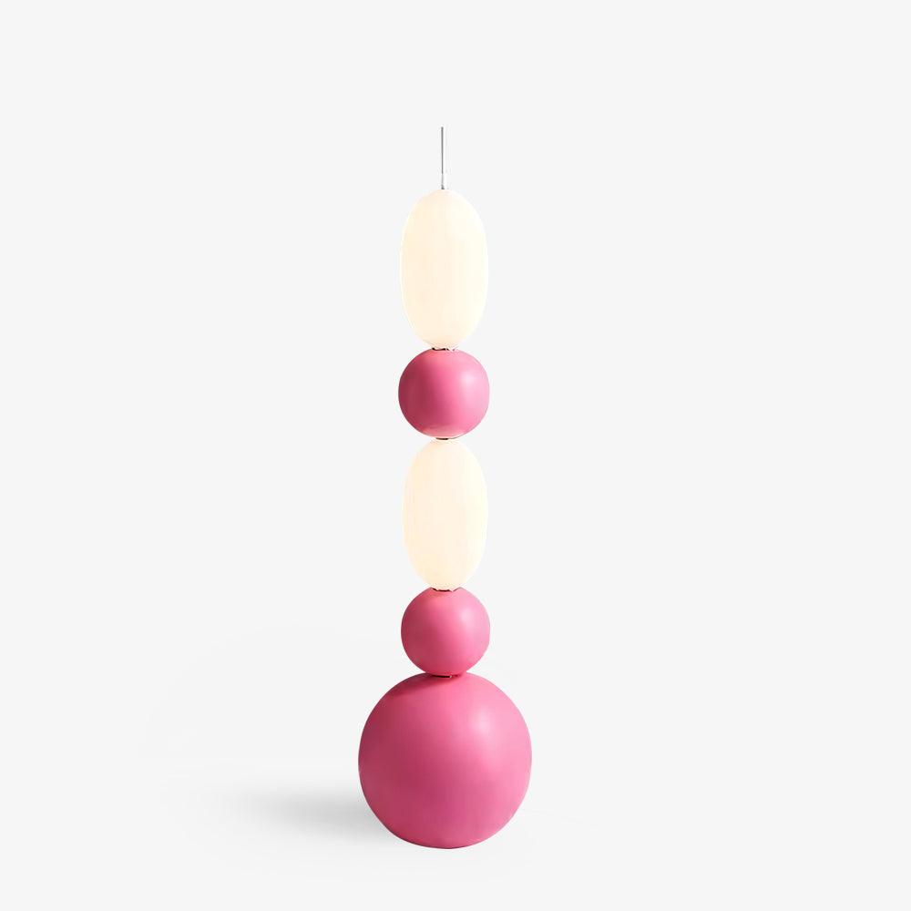 Pink stacked floor lamp with white oval shades, smaller pink spheres and a large round base on pale background