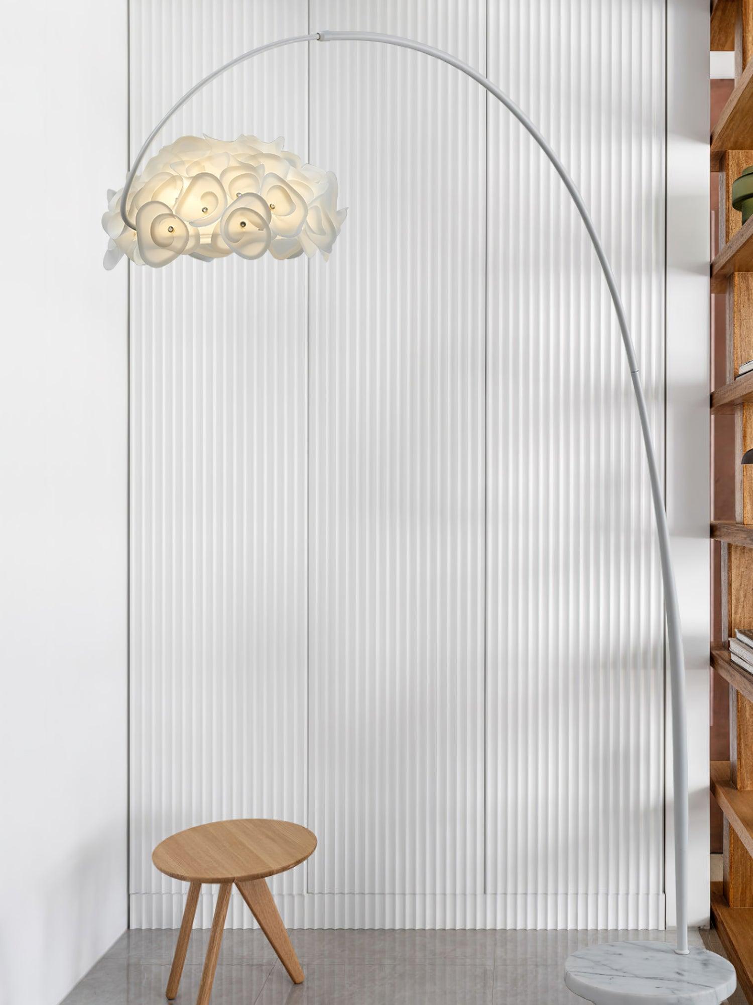 White arched petal lamp by ribbed wall and wooden bookshelf, small wooden stool and gray-veined round base