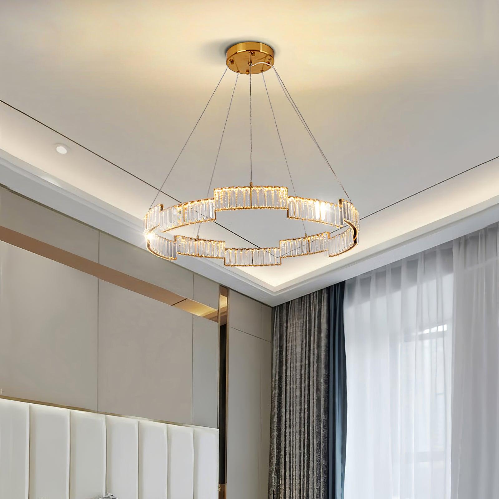 Upward bedroom view of a lit glass ring chandelier with pale headboard, wall panels, corner window and patterned curtains