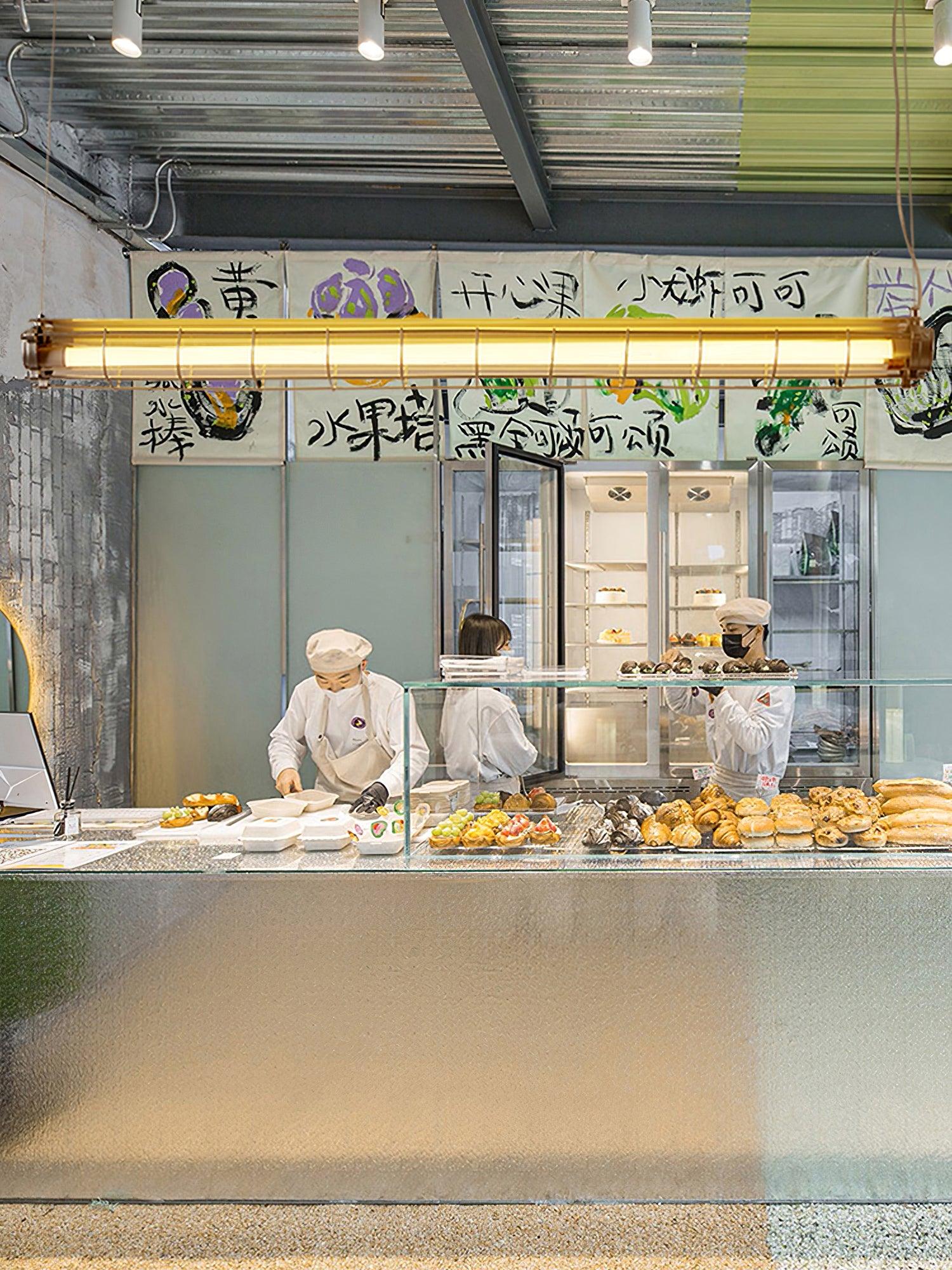 Artisan Glass chandelier above a bakery display counter with pastries and wall artwork