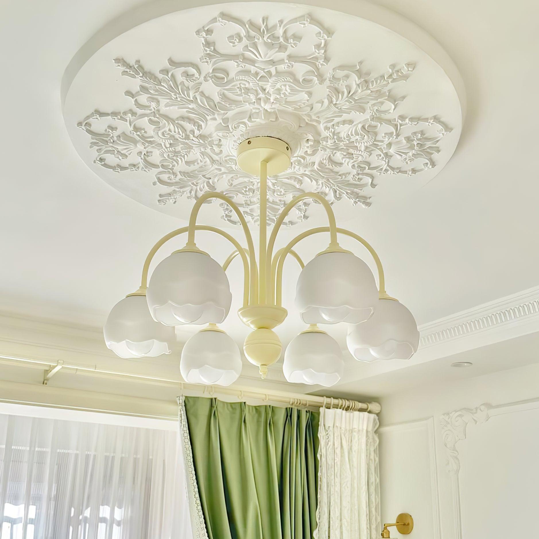 Cream curved-arm chandelier with white bell-shaped glass shades beneath a decorative ceiling rose