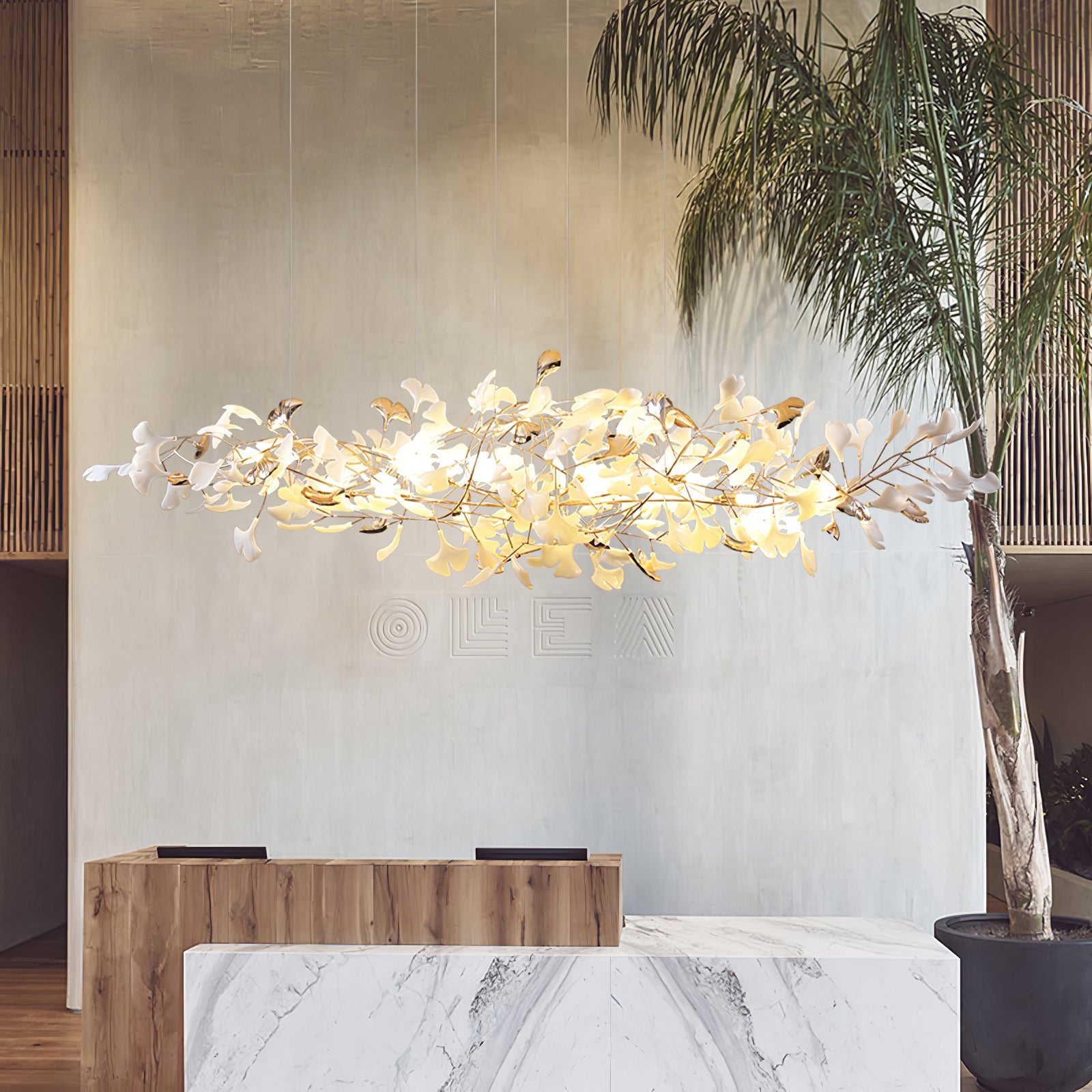 Horizontal leaf cloud above marble-and-wood counters, raised wall lettering and tall palm in a pale interior