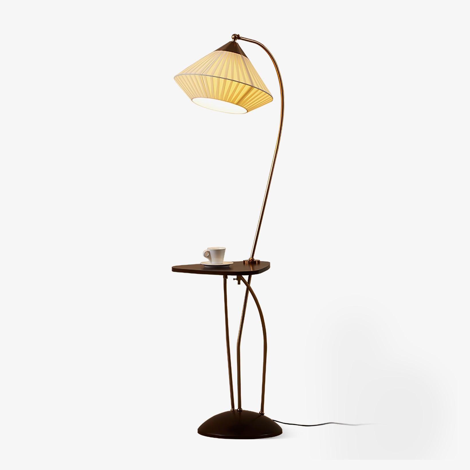 Isolated Curve lamp with curved brass-coloured supports, lit beige pleated shade, small dark table, cup and domed base