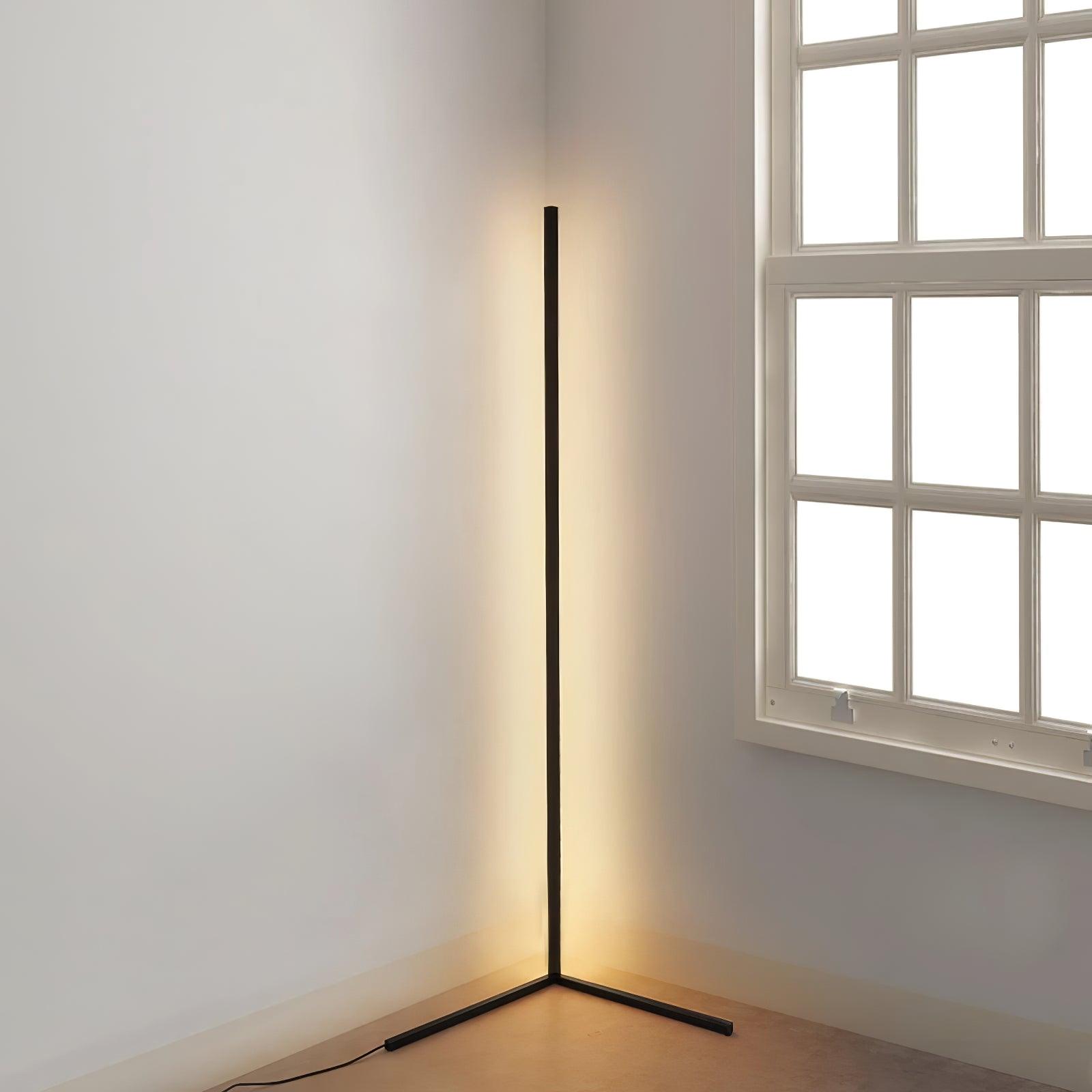Complete black corner lamp beside a multi-pane window, with angled feet and trailing power cord