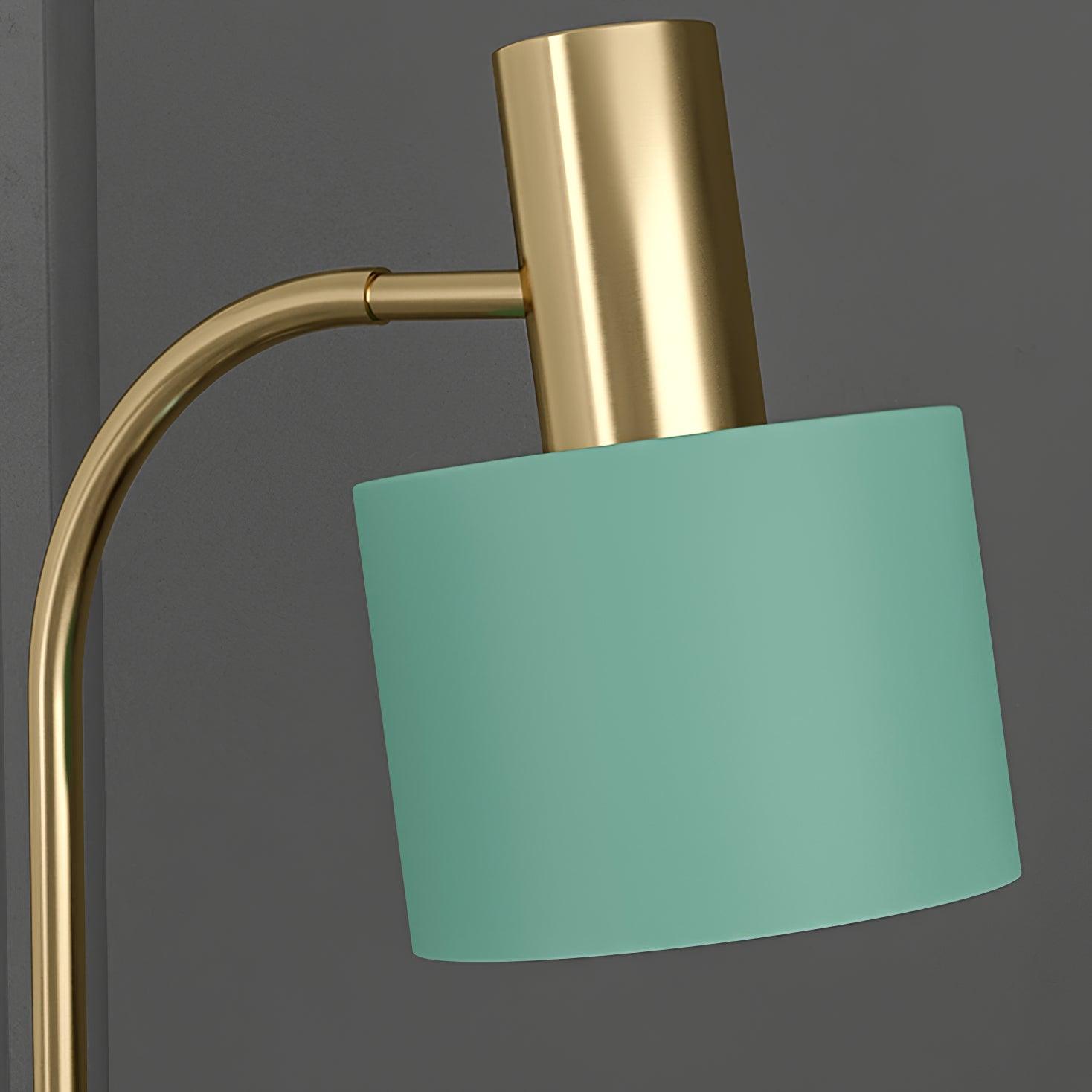 Close green cylindrical lampshade below gold cylindrical fitting on curved gold arm against gray background