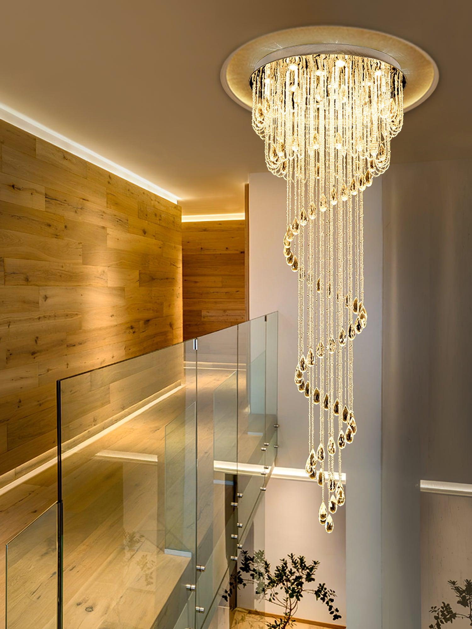 Long crystal spiral beside pale wood stairs and glass balustrade, with timber-clad wall and leafy branches below