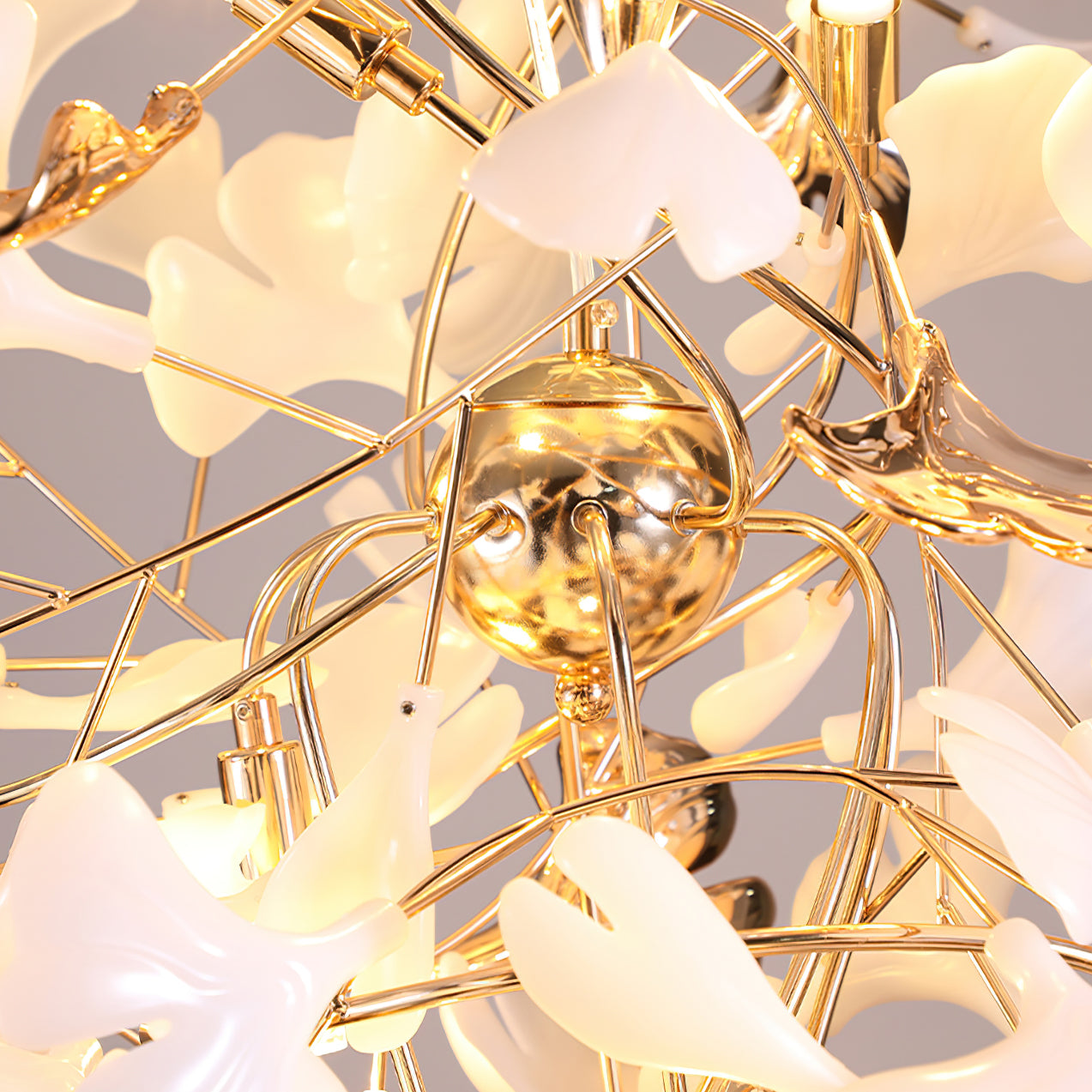 Underside detail of gold-tone spherical junction, curved stems, small lamp holders and white ginkgo leaves