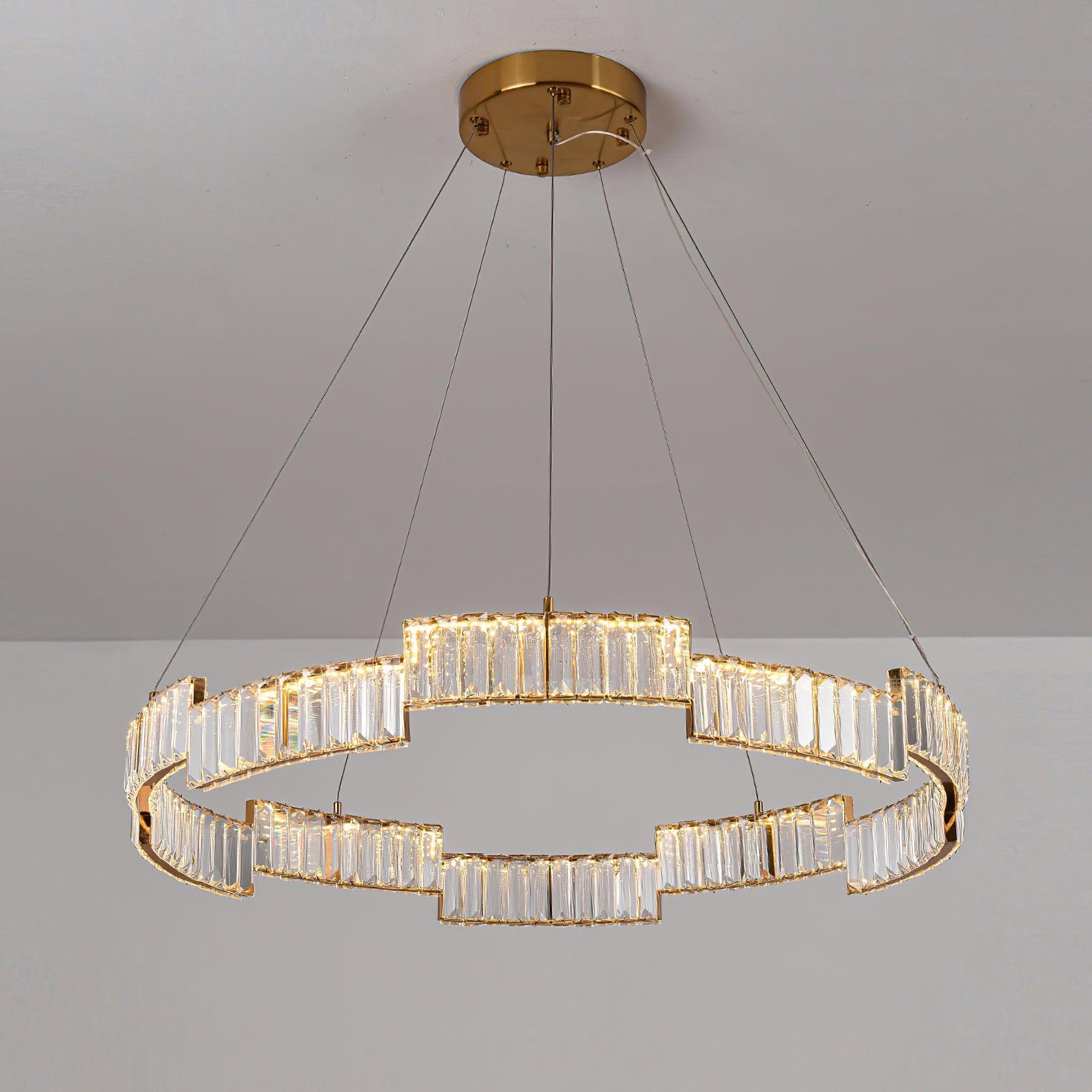 Lit stepped glass ring chandelier with suspension wires and round canopy against a pale ceiling and wall