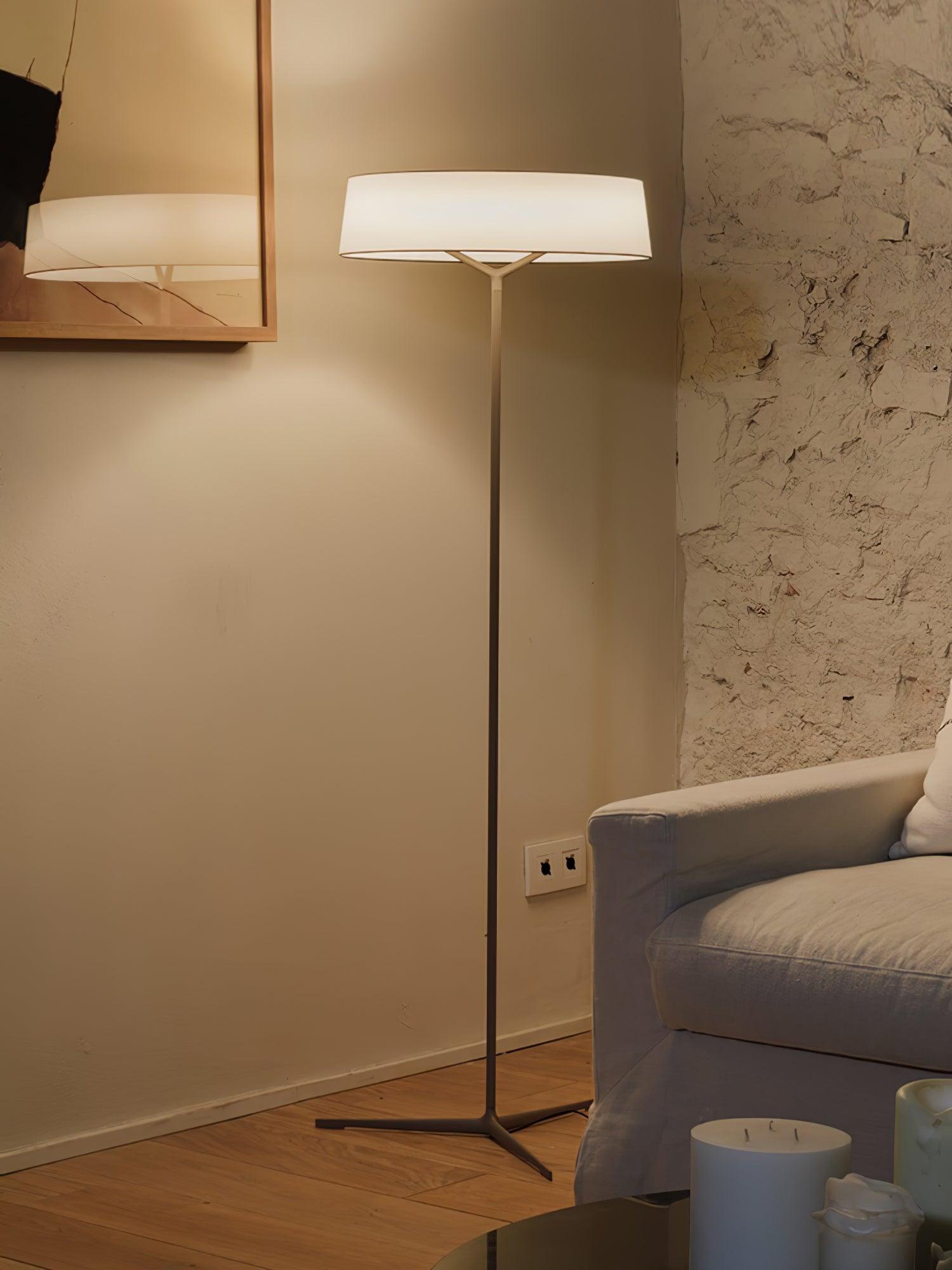 Slender floor lamp beside a wall mirror and sofa