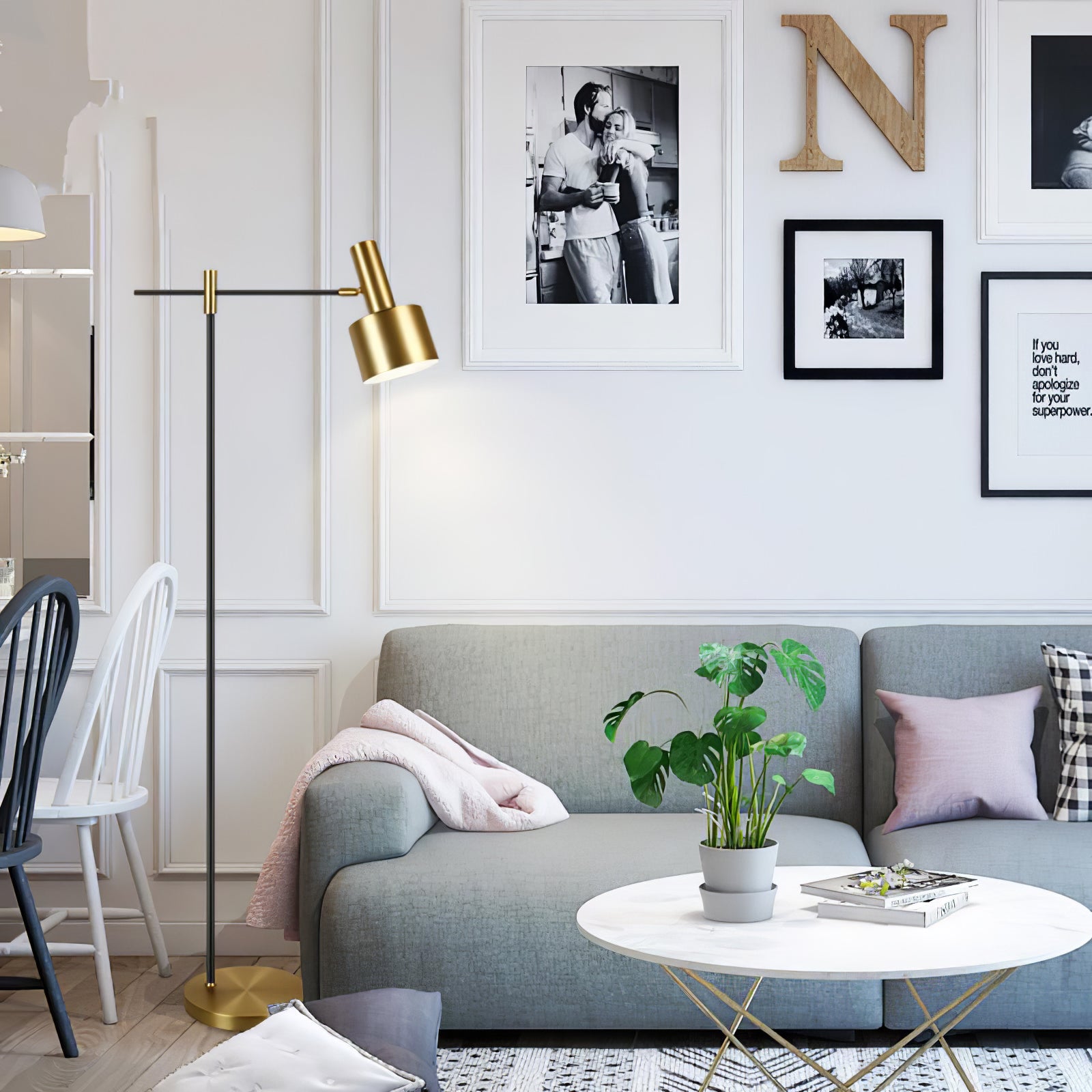Wide grey-sofa scene with black and gold floor lamp, pink throw, plant and books on white coffee table
