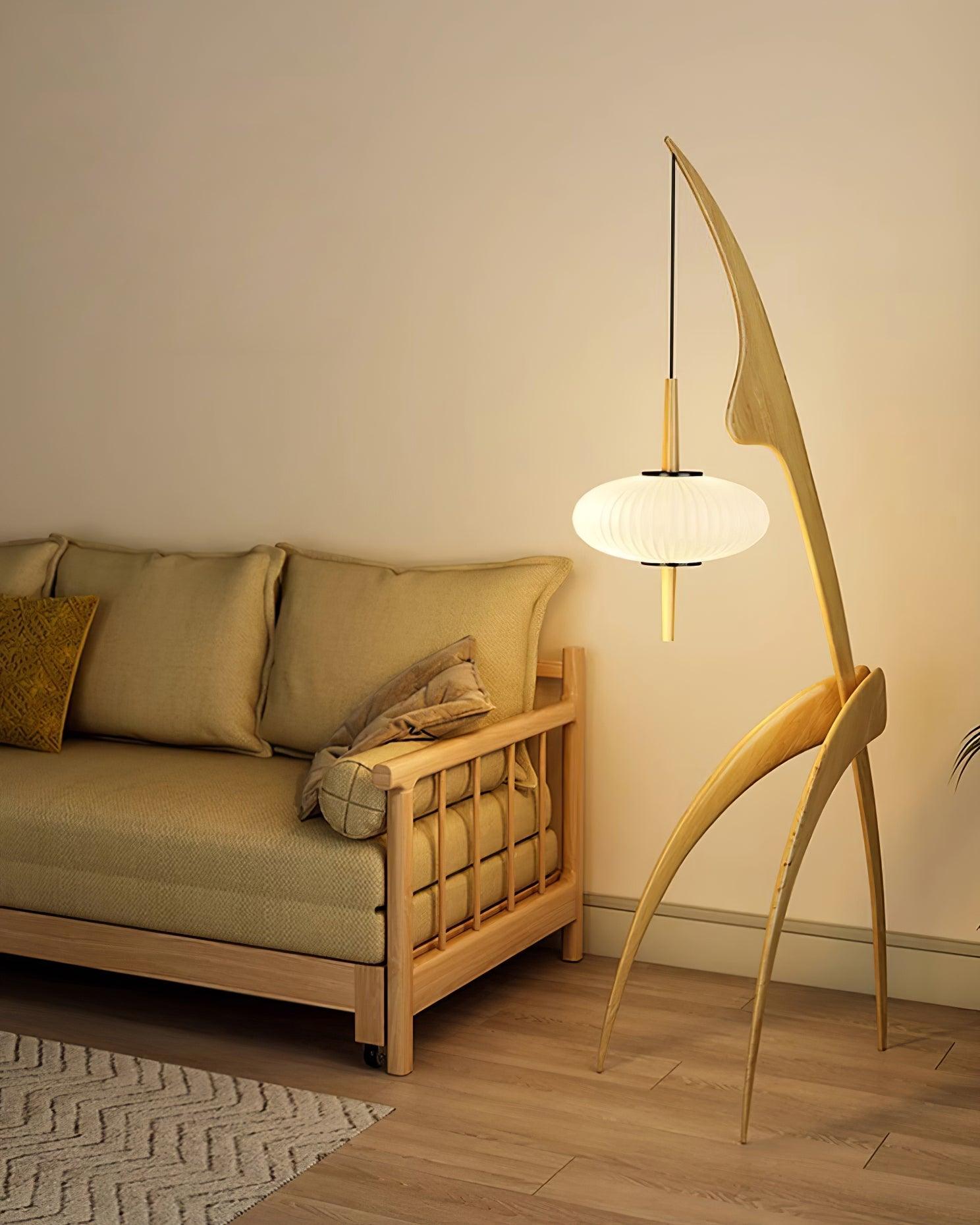 Light wood Mantis lamp with curved legs next to a sofa