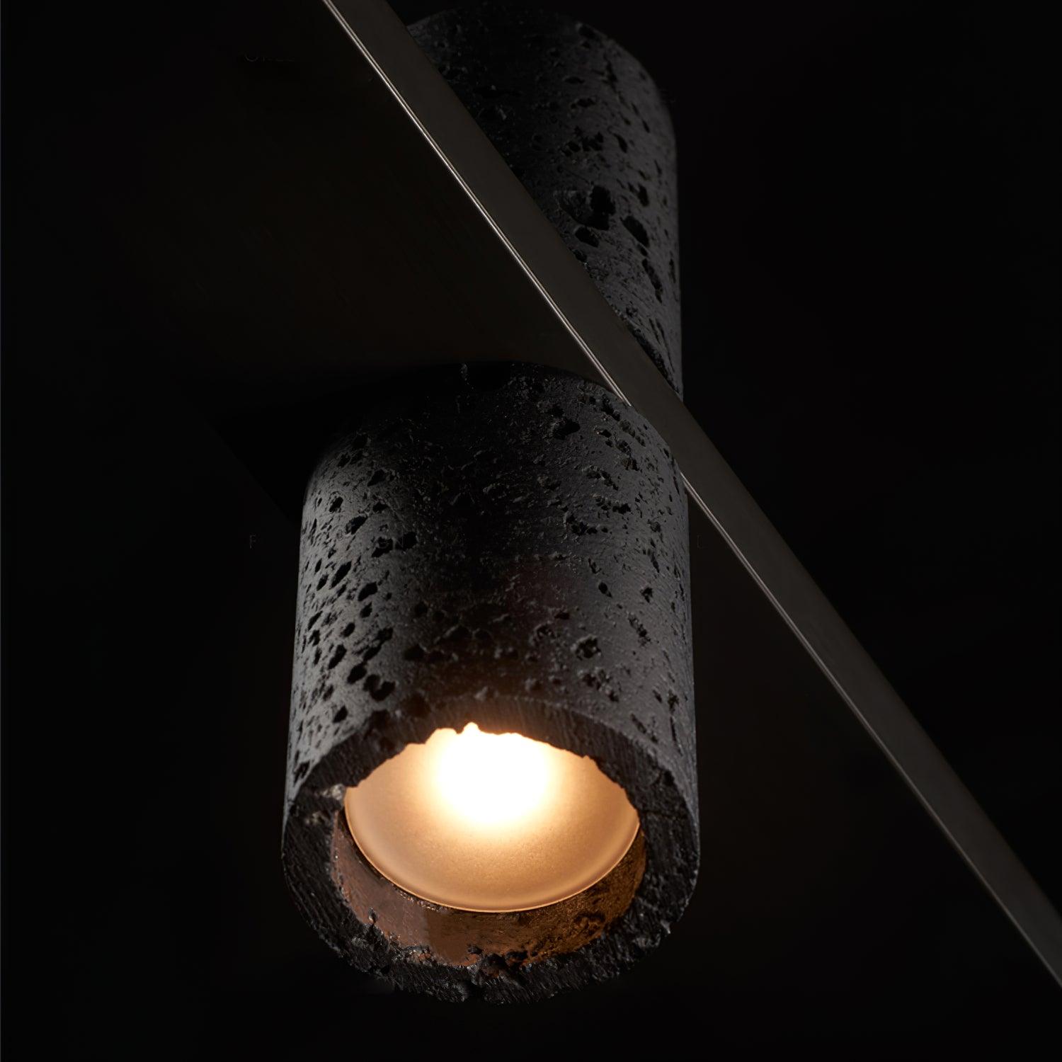 Close underside of porous black stone cylinder, showing glowing recessed circular face, irregular stone rim and diagonal bar.