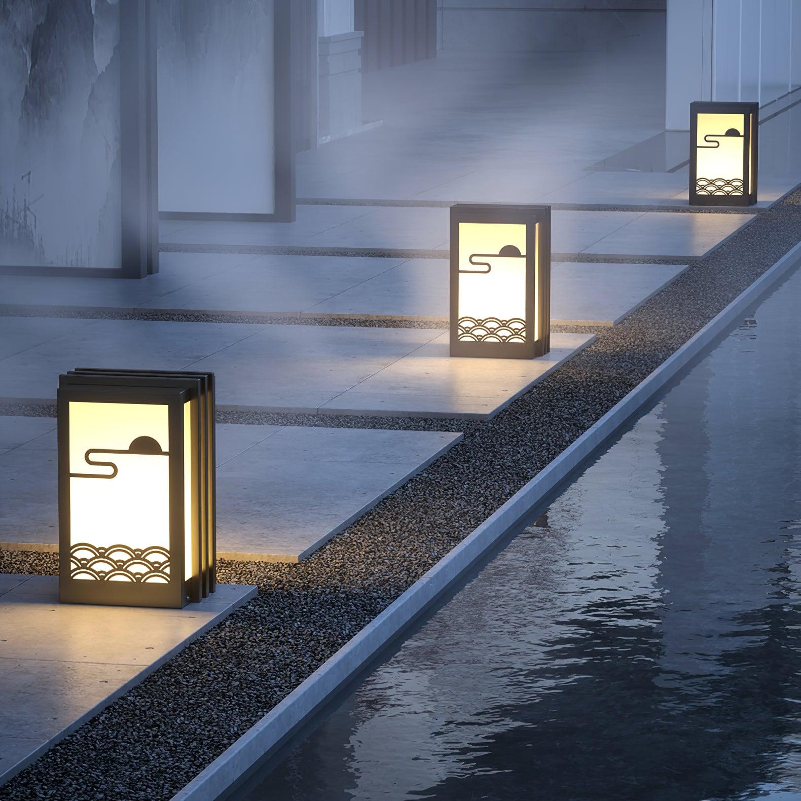 Three short garden lanterns on separate paving pads beside gravel and a narrow reflecting water channel