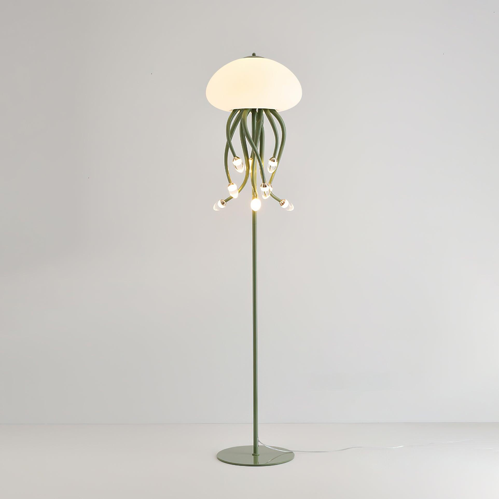 Green nine-arm floor lamp against pale background, showing glowing dome, hanging droplet lights, full stem and round base.