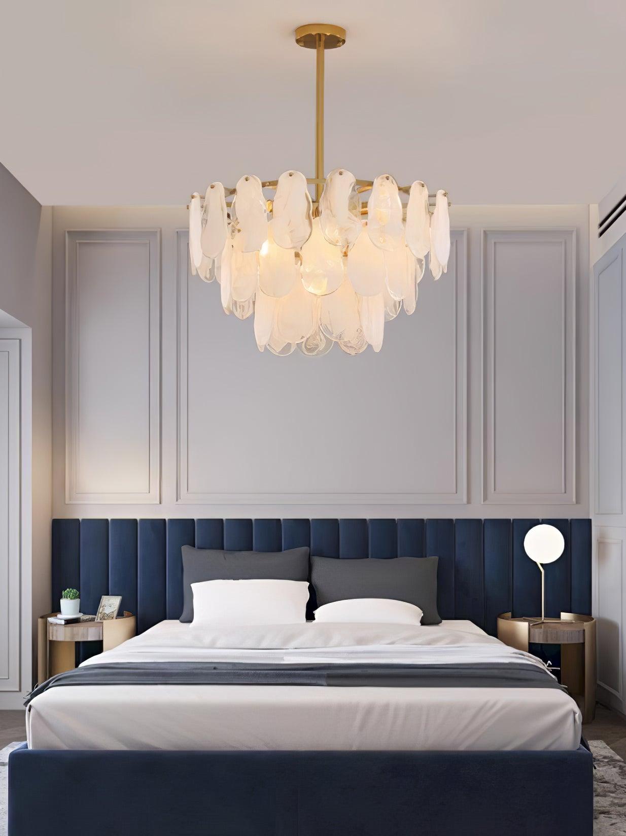 Round Cloud glass pendant above a bed with a blue upholstered headboard