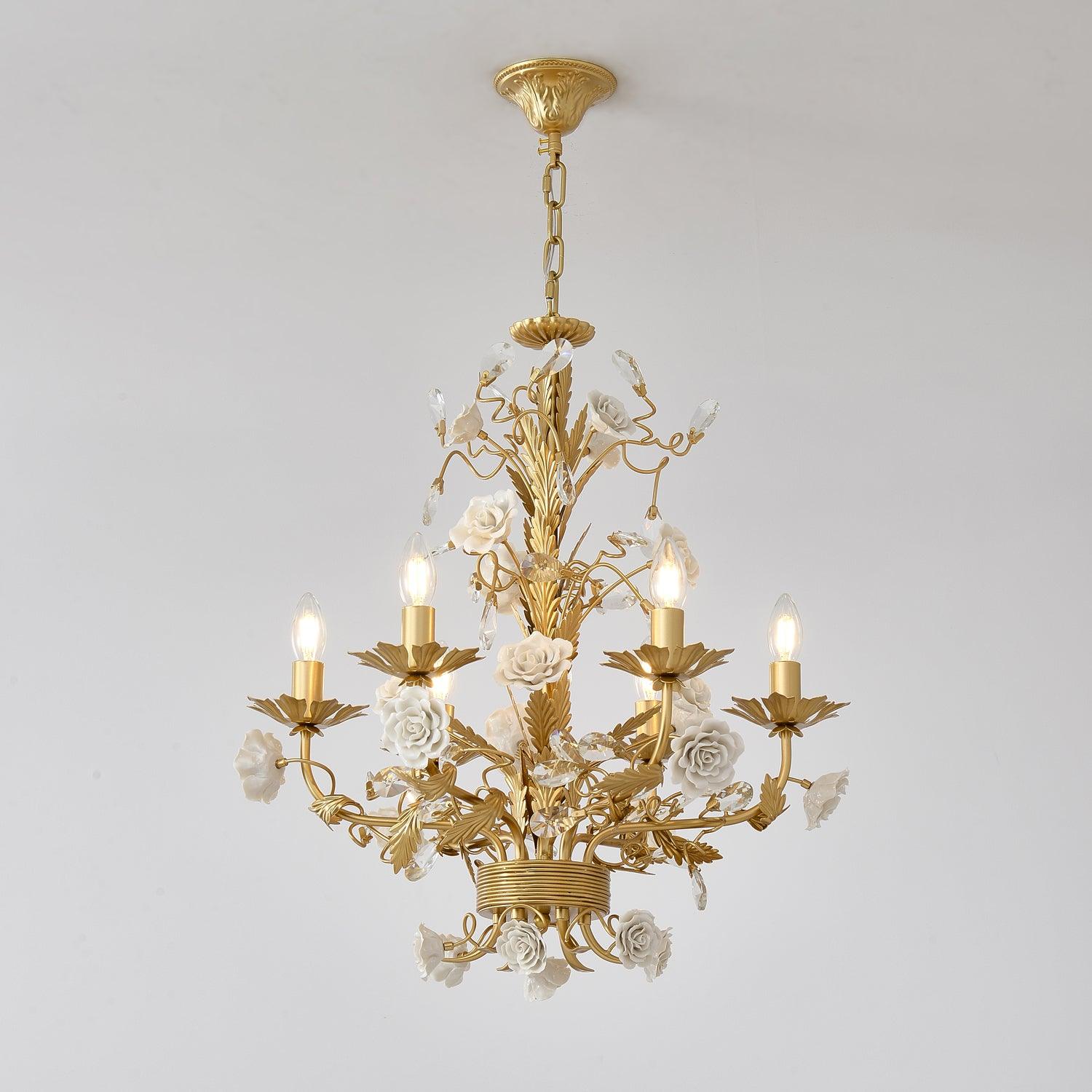 Full lit White Rose chandelier against pale gray, with golden leafy stem, curved candle arms, white roses and clear buds