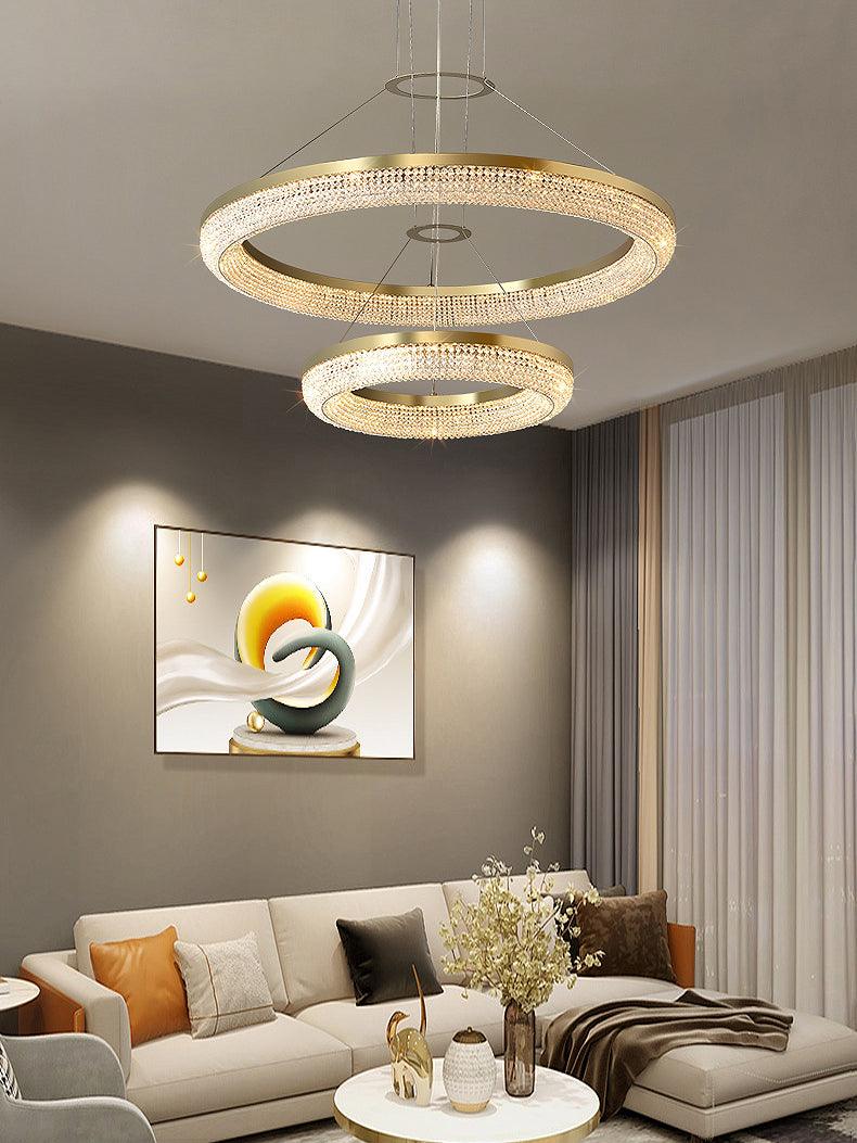 Two-ring crystal chandelier above a sofa and coffee table beneath abstract wall artwork