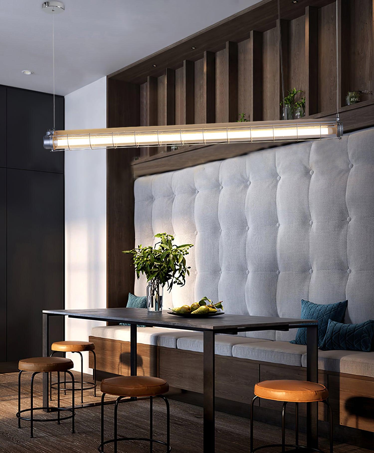Artisan Glass linear chandelier above tables and dark upholstered seating beside tall vertical wall panels