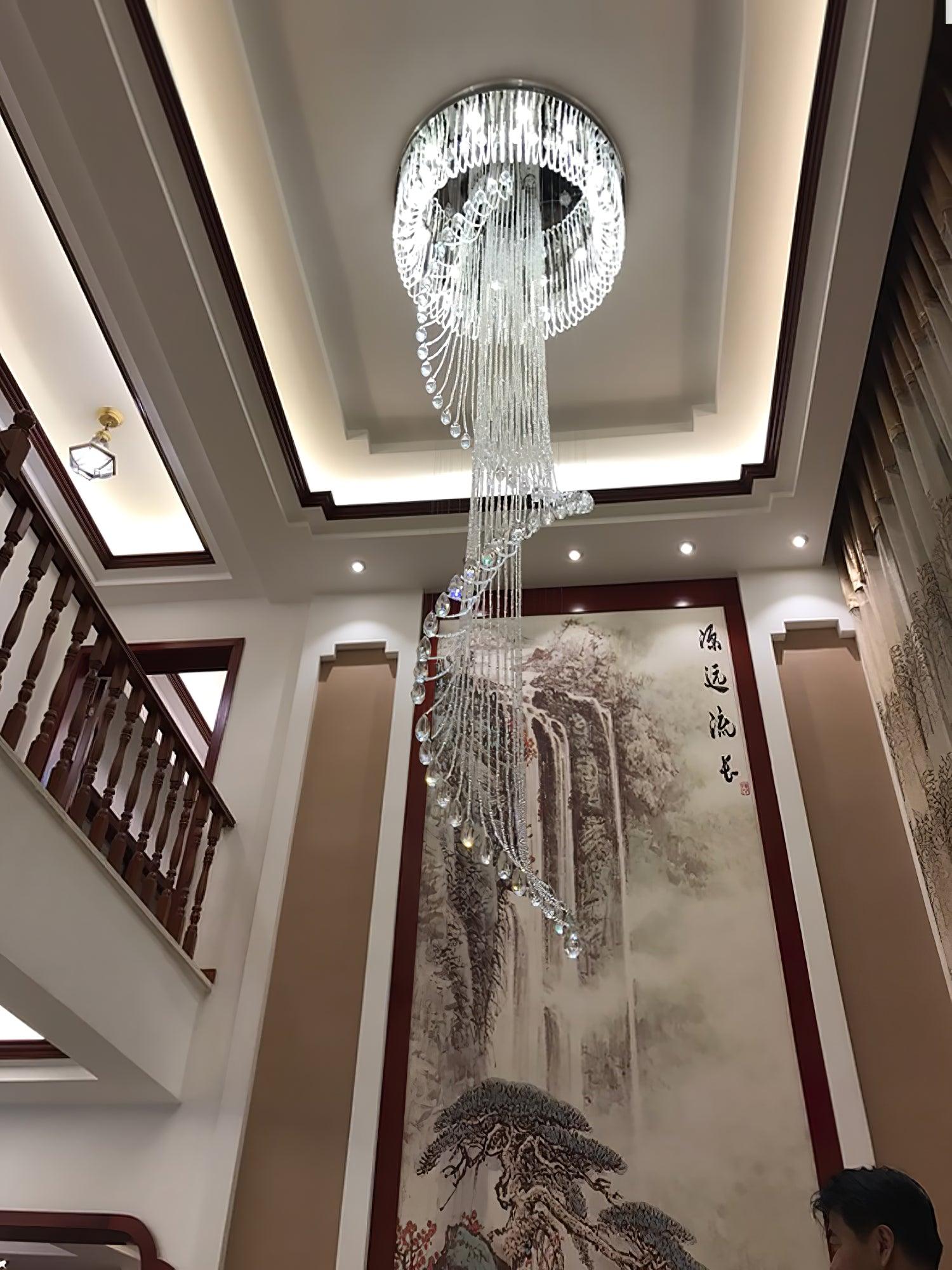 Lit crystal spiral in a tall stair void, with dark wood balusters, framed landscape artwork and curtain